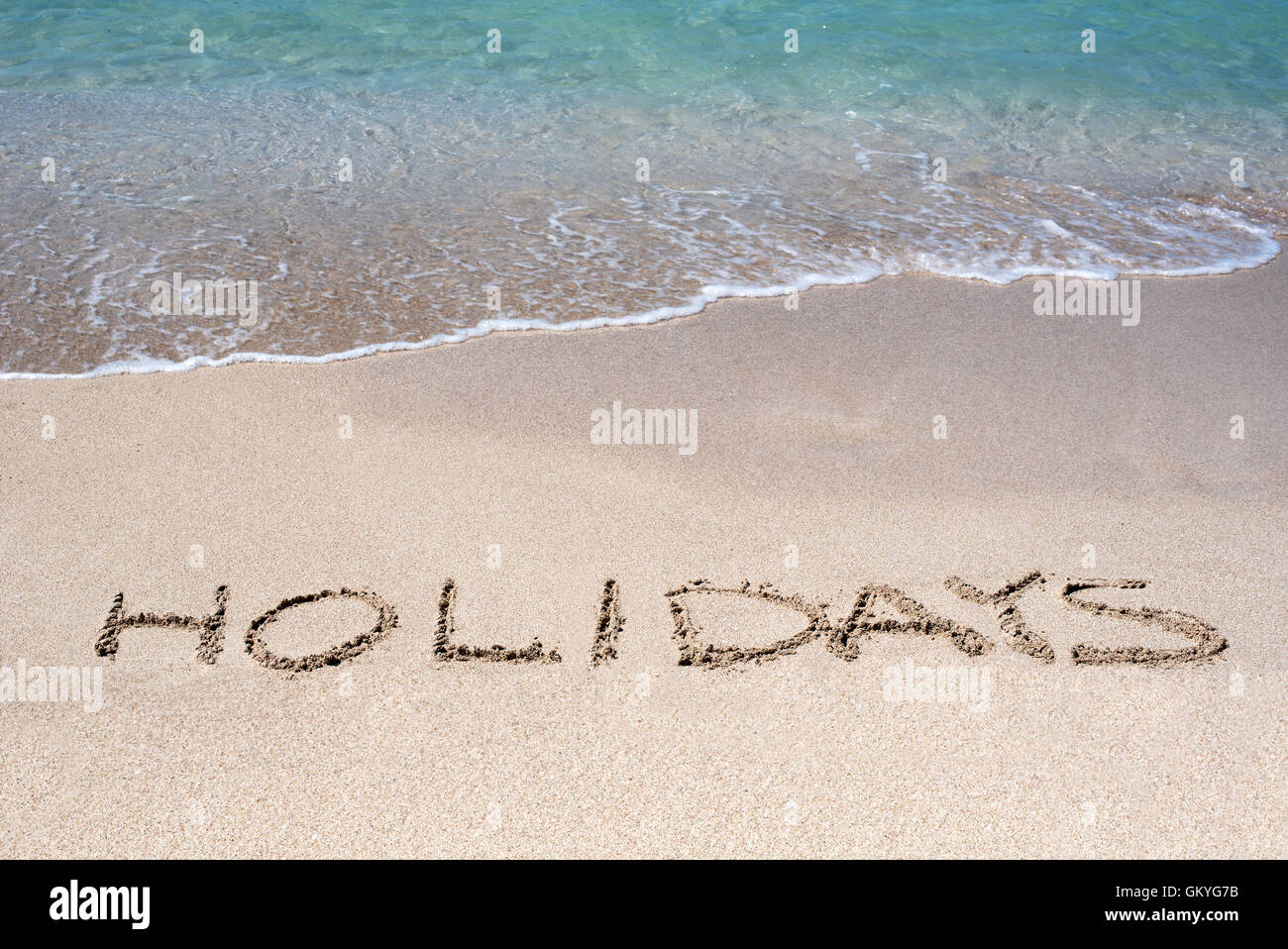 Wort-Urlaub an einem tropischen Strand im goldenen Sand skizziert Stockfoto