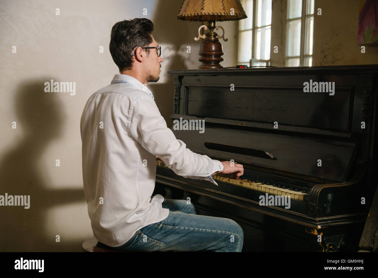 dunkelhaarige Mann spielt auf dem Klavier sitzen auf dem Stuhl. Er ist von diesem Spiel inspiriert. Stockfoto