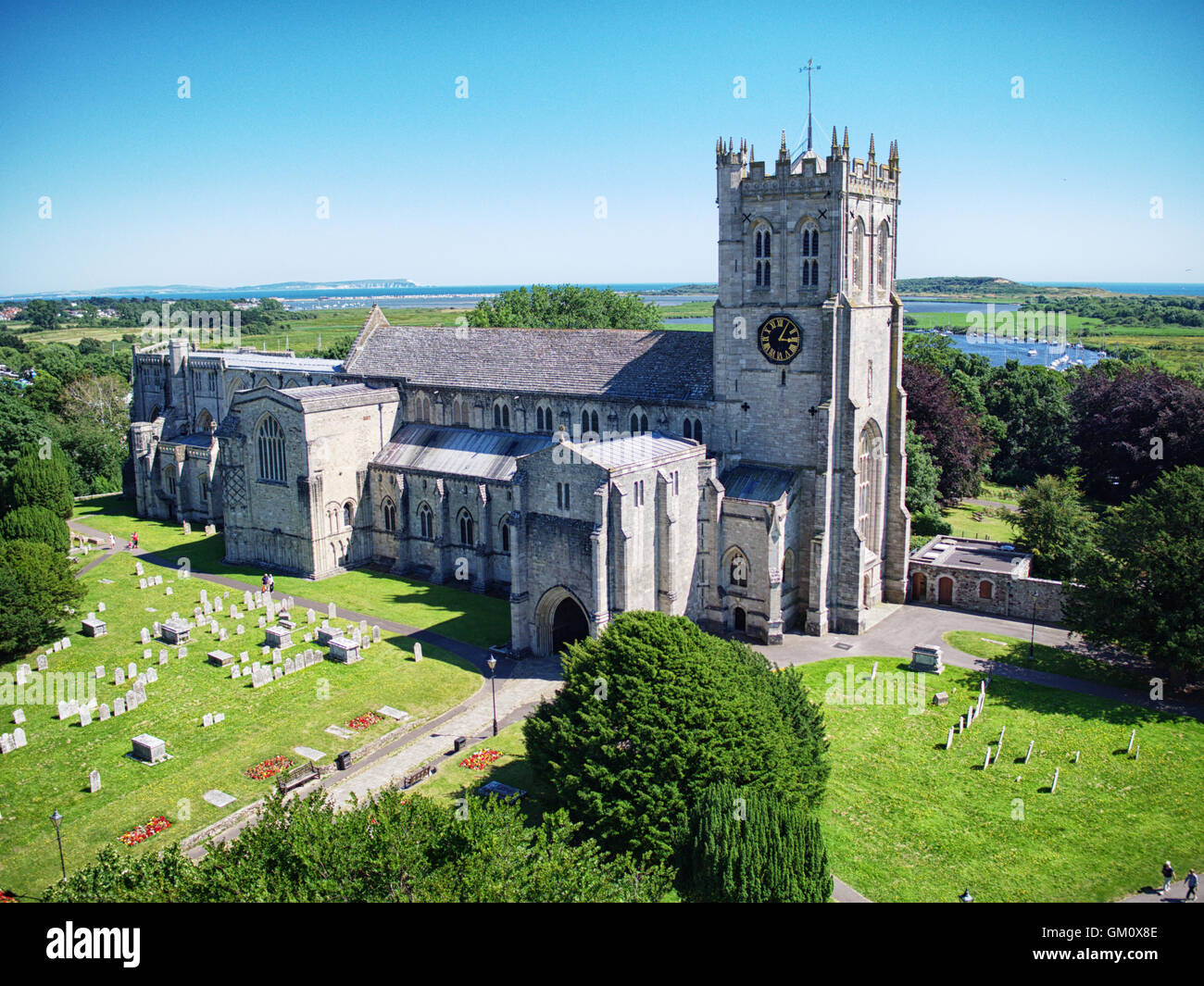 Luftaufnahme von Christchurch Priory in Christchurch, Dorset, England. Die Nadeln Landzunge auf der Isle Of Wight in der Ferne. Stockfoto