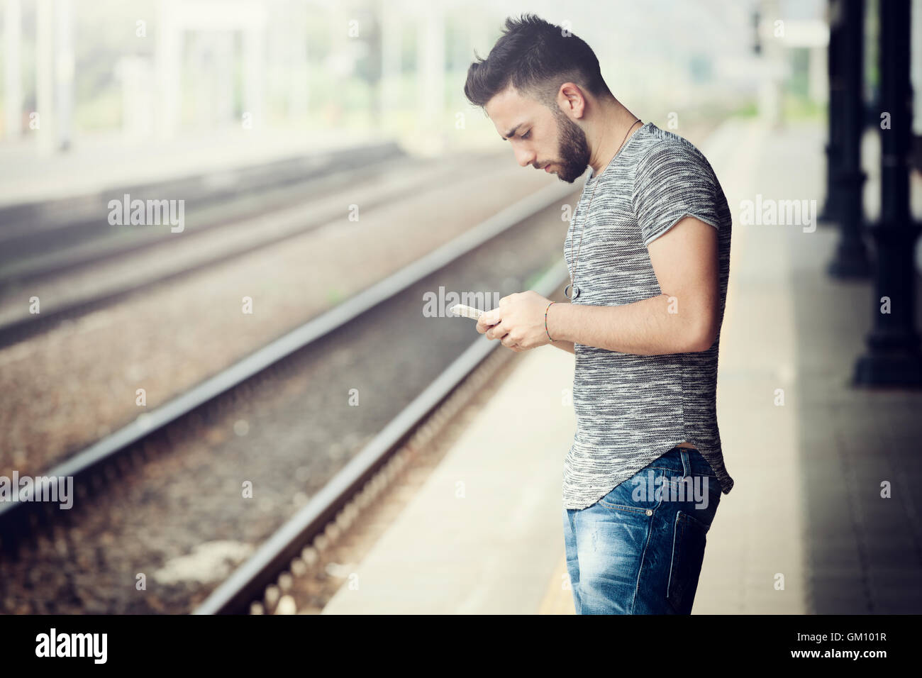 Junger Mann mit Smartphone am Bahnhof. Stockfoto