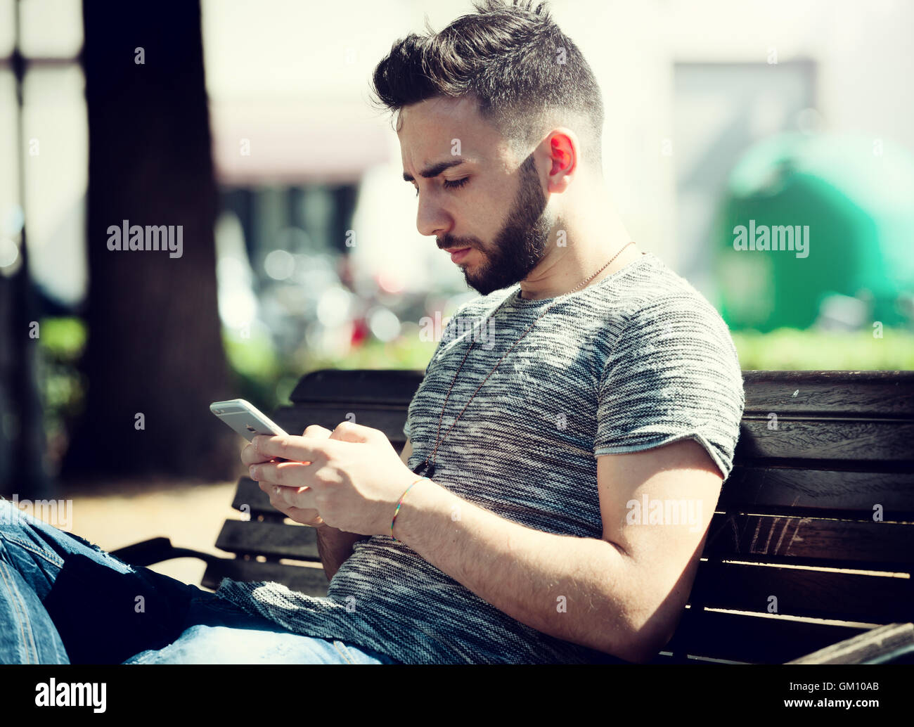 Junger Mann im Park mit Smartphone an einem sonnigen Tag. Stockfoto