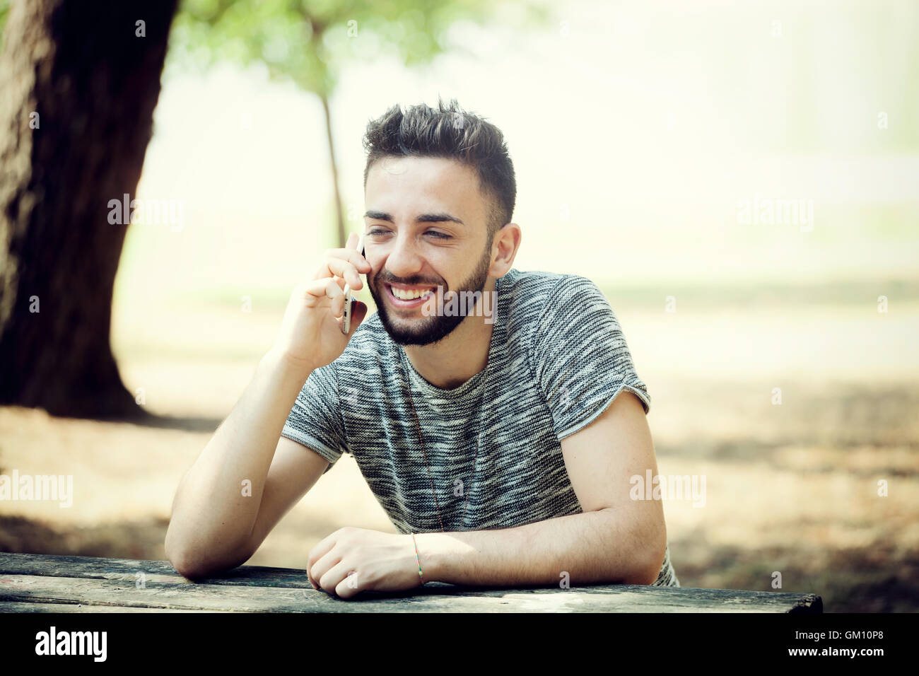 Junger Mann im Park mit Smartphone an einem sonnigen Tag. Stockfoto