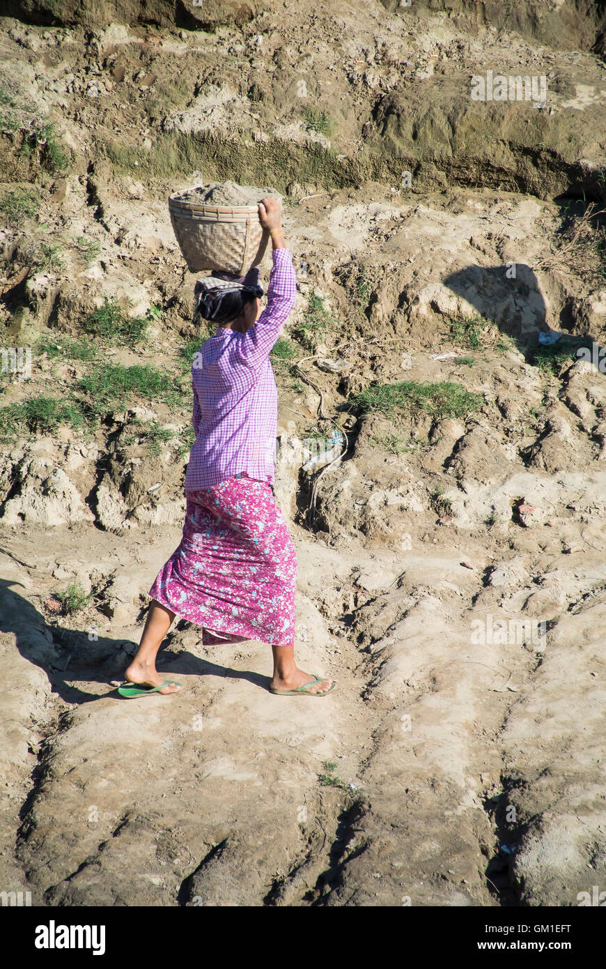 Dorf-Frau mit Ton vom Flussufer an Spitze der Bank, Myanmar Stockfoto