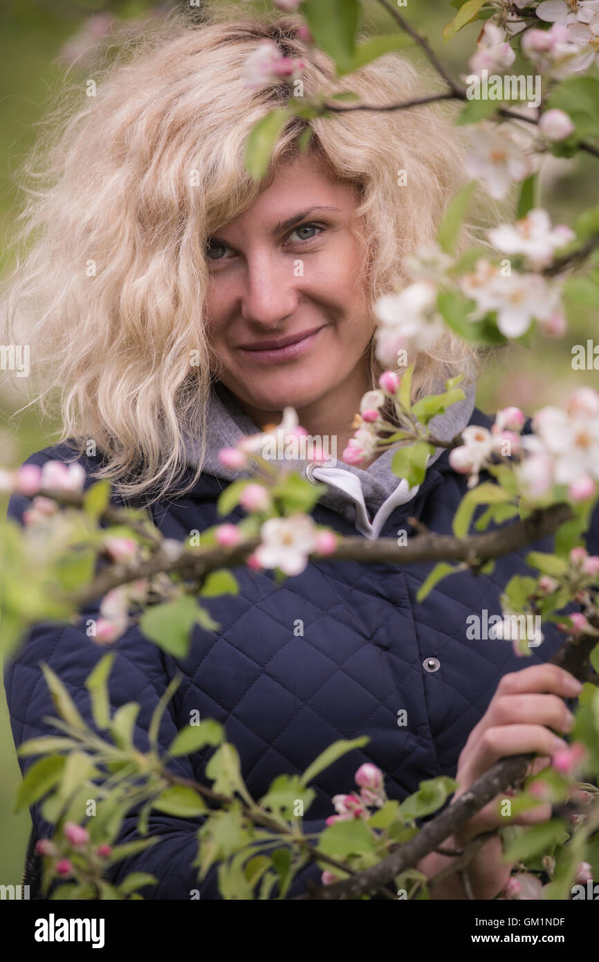 Porträt der schönen Frau mit lockigem Haar in der Nähe der Blüte apple tree. Stockfoto