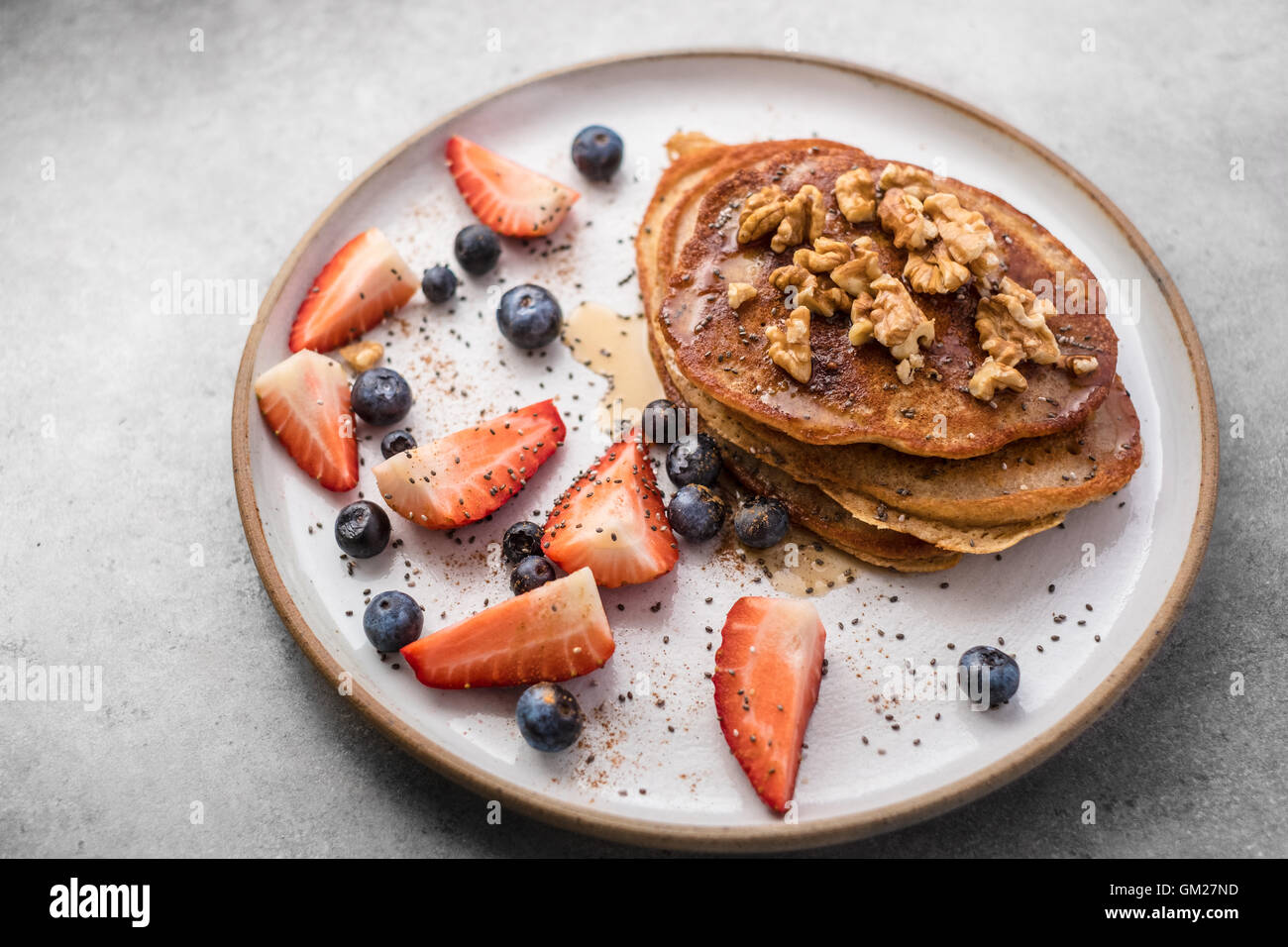 Frischer Heidelbeer-Pfannkuchen mit Honig, Erdbeeren, Heidelbeeren, Walnüssen und Chia-Samen Stockfoto