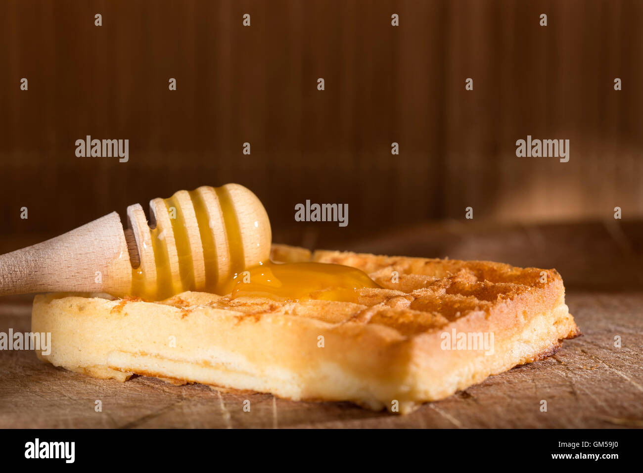Honig auf einem frischen Waffeln über hölzerne Hintergrund Stockfoto