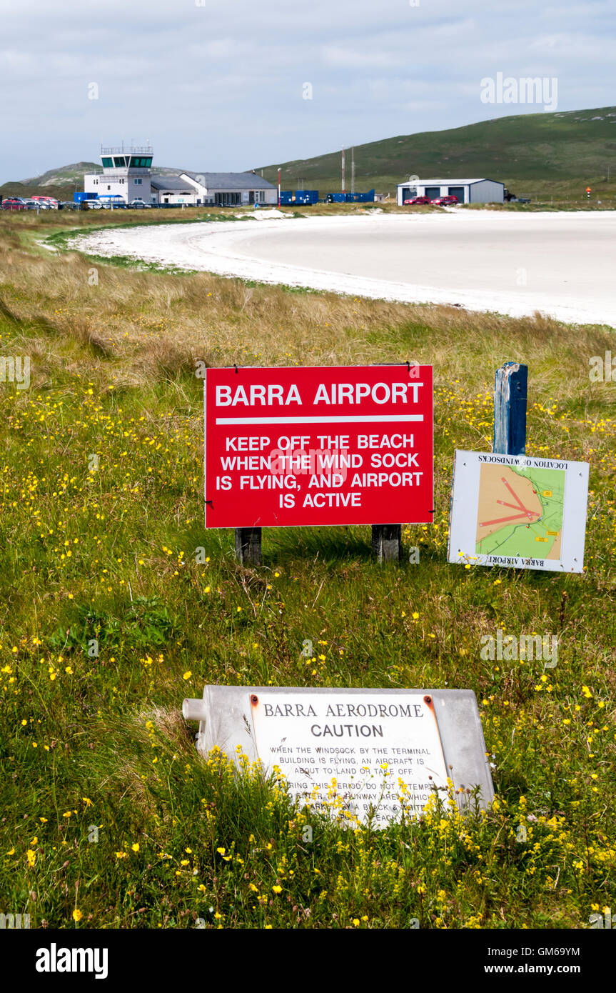 Ein Schild warnt die Menschen um den Strand von Traigh Mhor fernzuhalten, wenn Barra Airport in Betrieb ist.  Control Tower im Hintergrund. Stockfoto