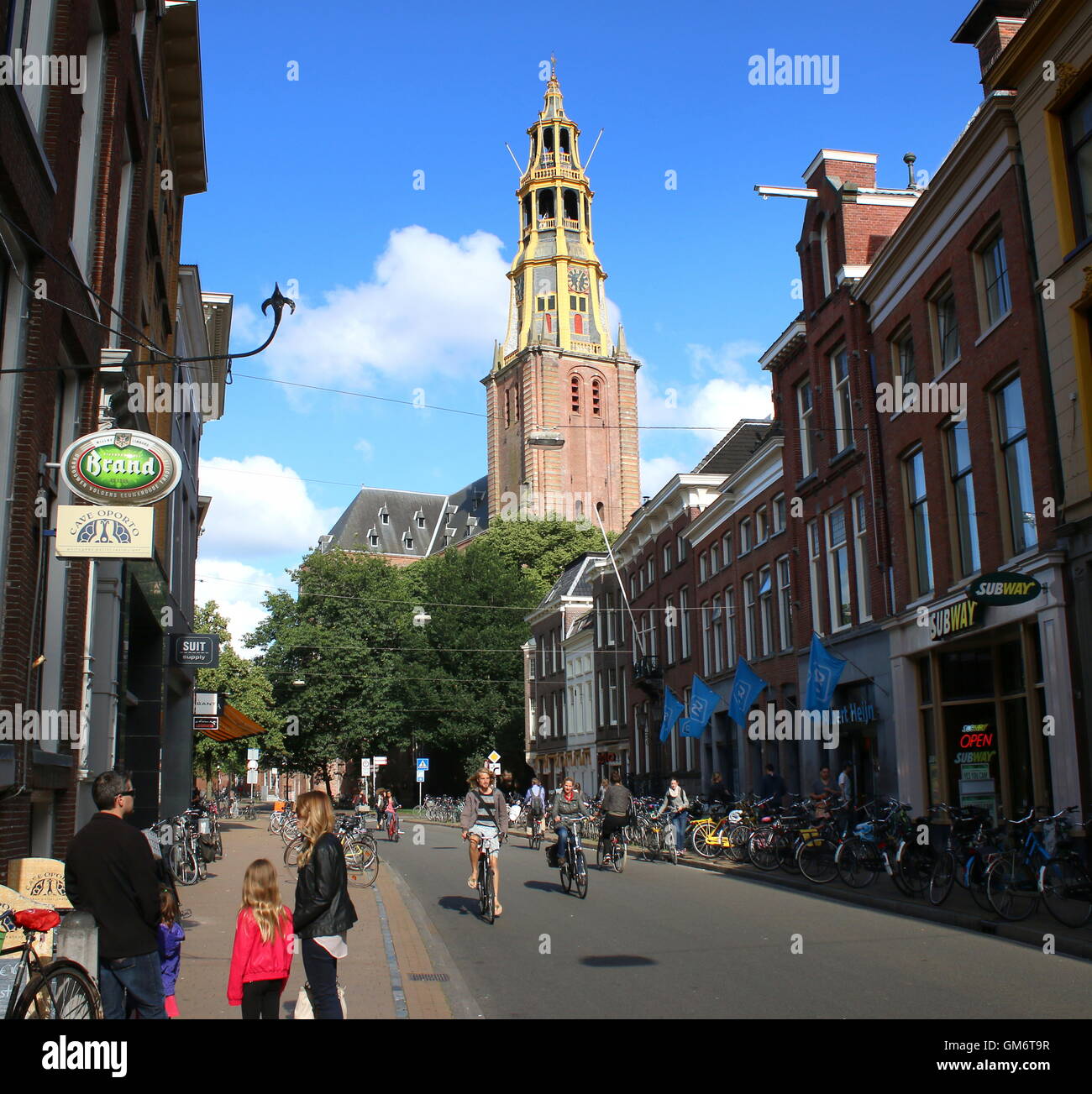 Menschen beim Einkaufen in Brugstraat (Bridge Street) in Groningen, Niederlande. 17. Jahrhundert Kirche Der Aa-Kerk im Hintergrund. Stockfoto