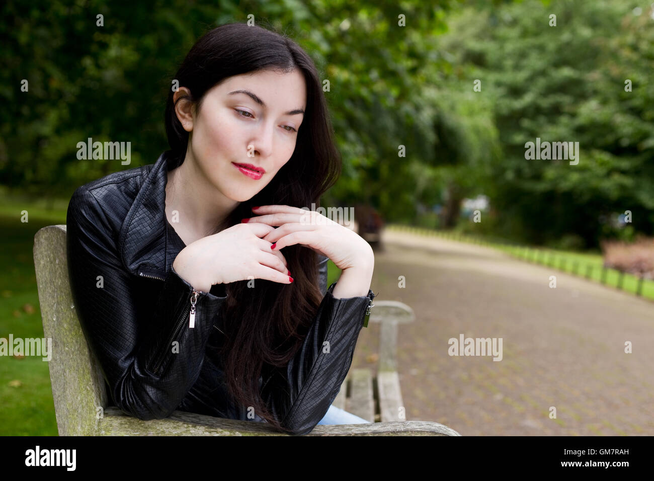 junge Frau, die nachdenklich im park Stockfoto