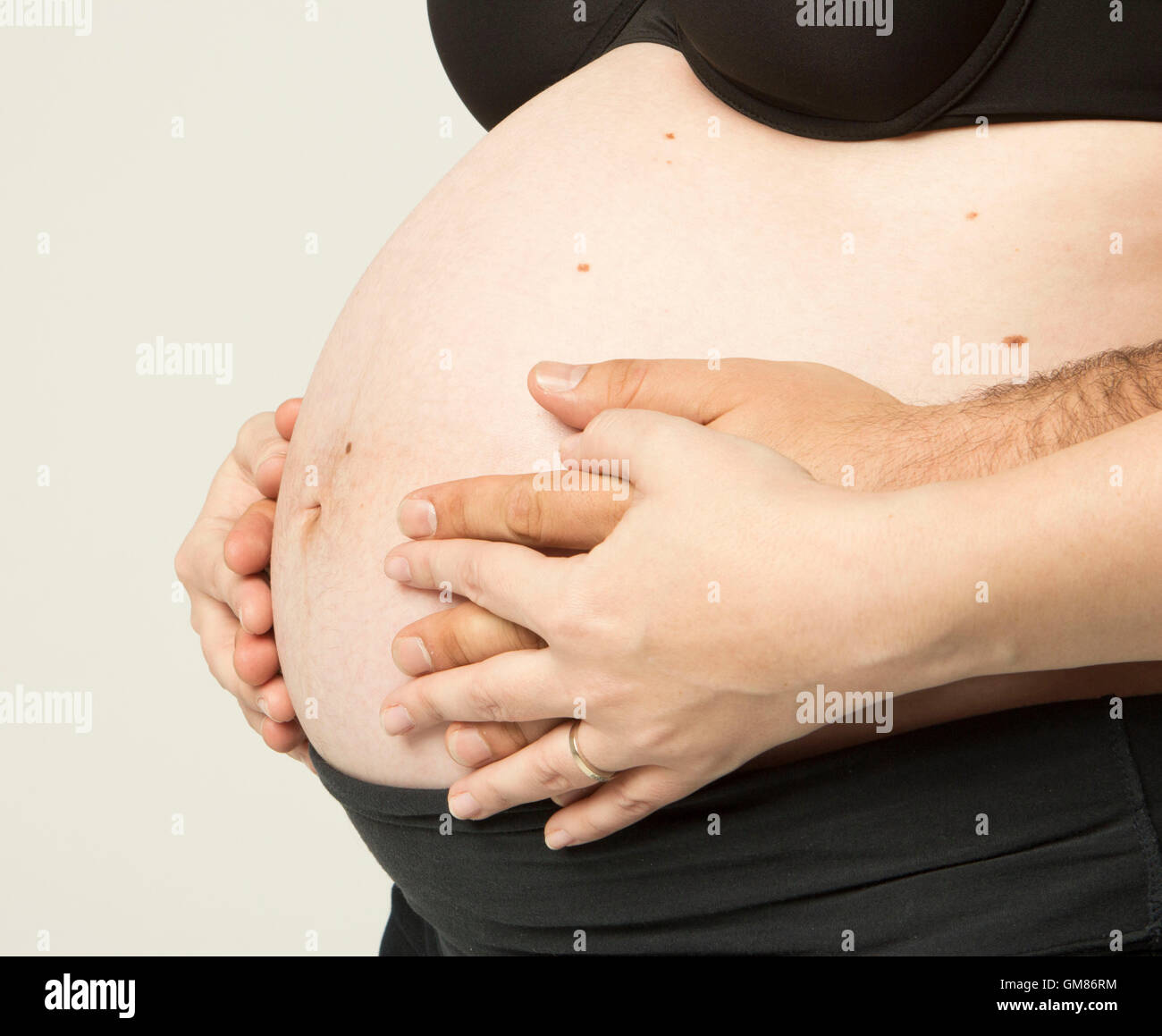 Schwangere Frau hielt ihre Hände auf schönen Bauch Stockfoto