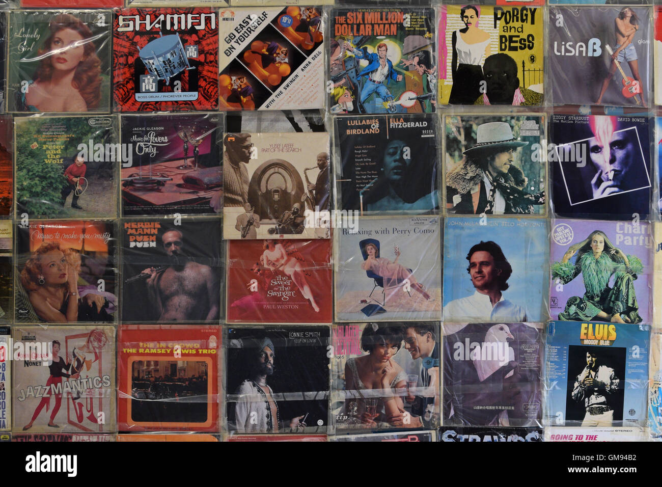 Wand mit alten Vinyl Platten Vintage Lp Musikalbum deckt in Plastikhüllen Hintergrund. Stockfoto