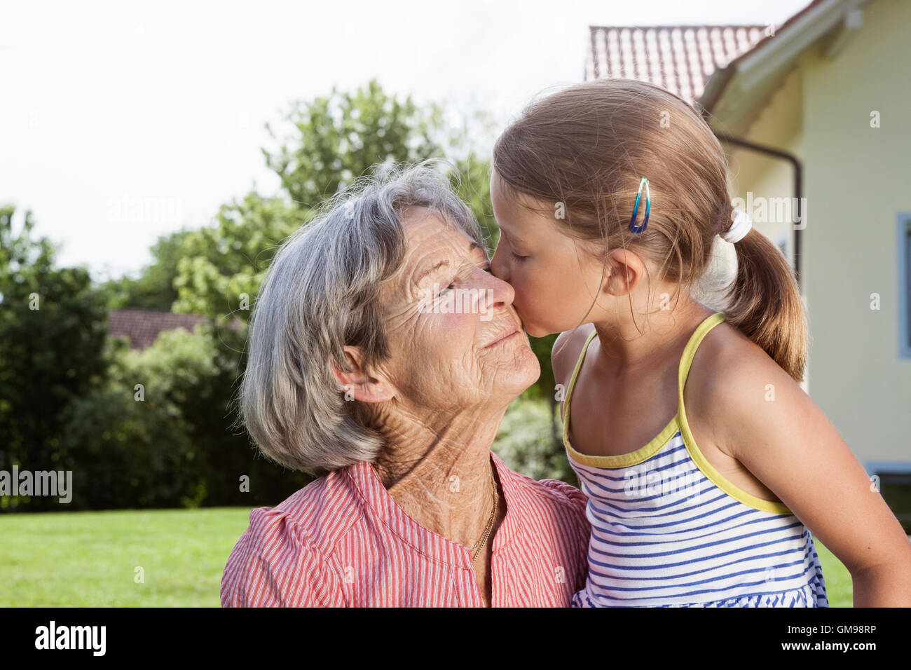 Enkelin küssen Großmutter im Garten Stockfoto