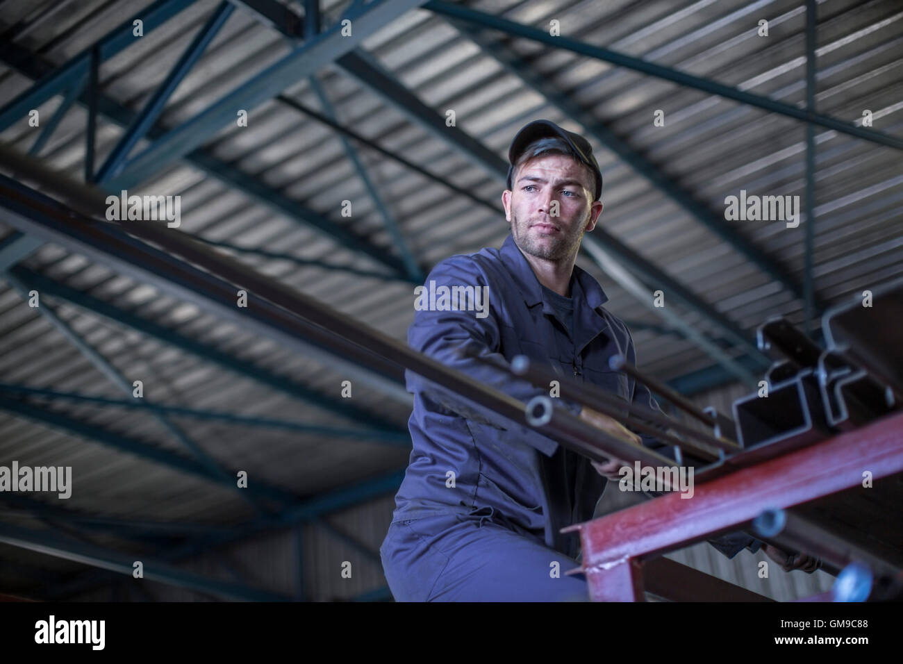 Mechaniker in der Werkstatt unter Stabstahl aus Hochregal Stockfoto