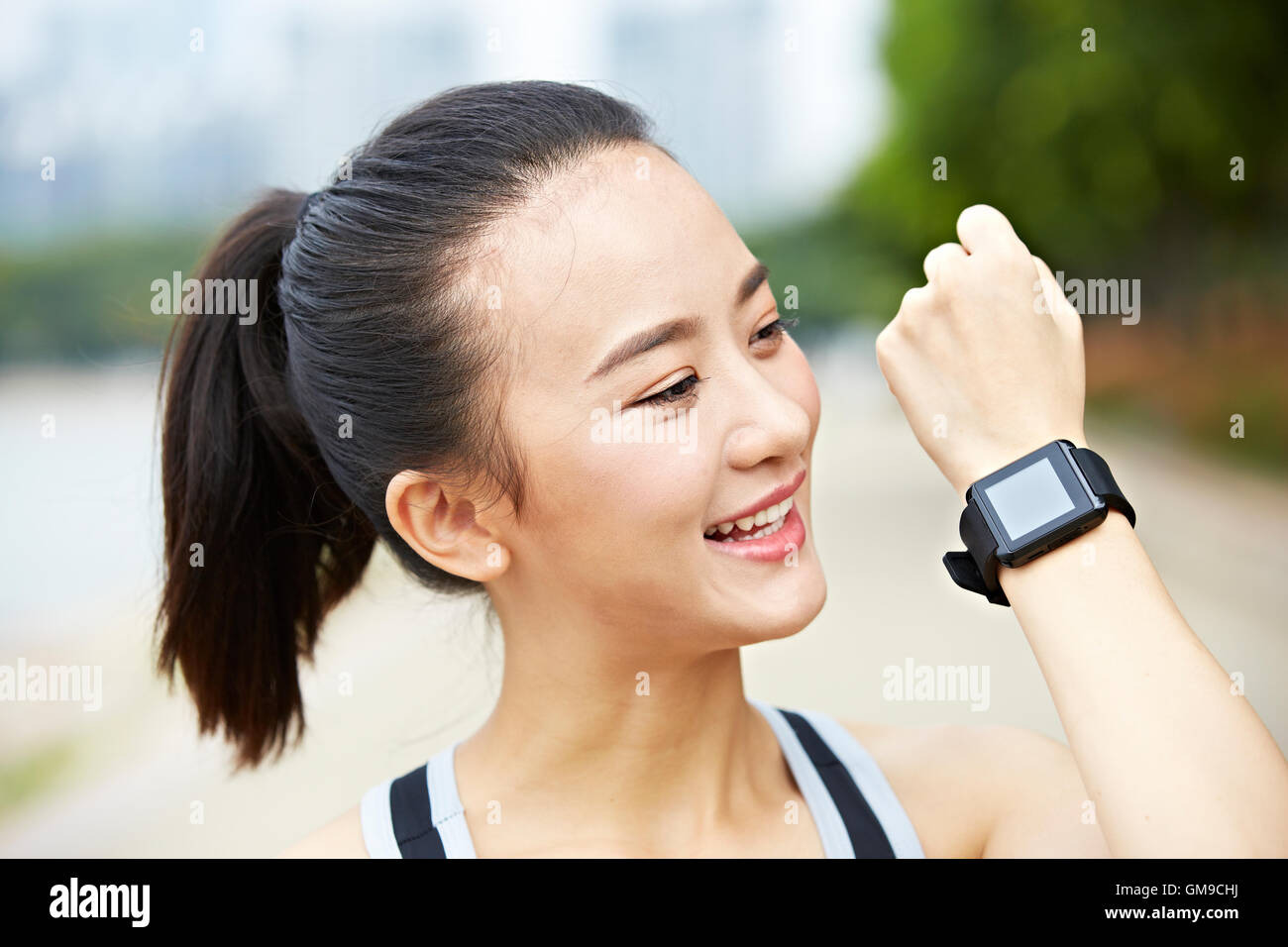 junge Asiatin Läufer zeigen tragbare Fitnessgerät (ansehen) und lächelnd. Stockfoto