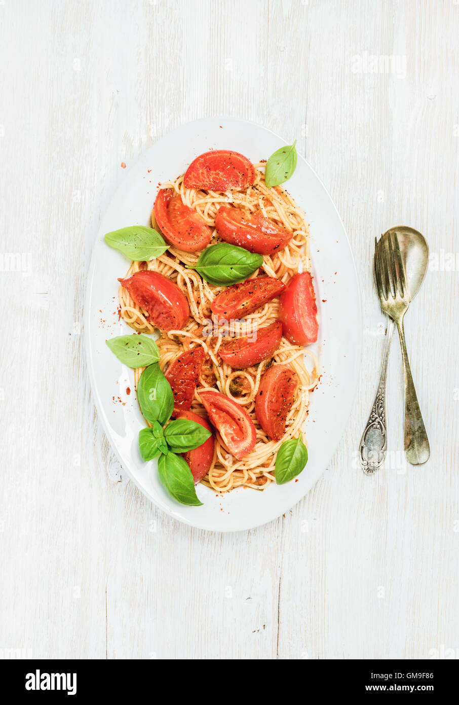 Pasta mit gebratenen Tomaten und Basilikum in weißem Holz Hintergrund Stockfoto