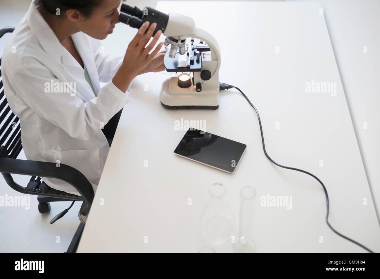 Blick durch das Mikroskop Wissenschaftlerin Stockfoto