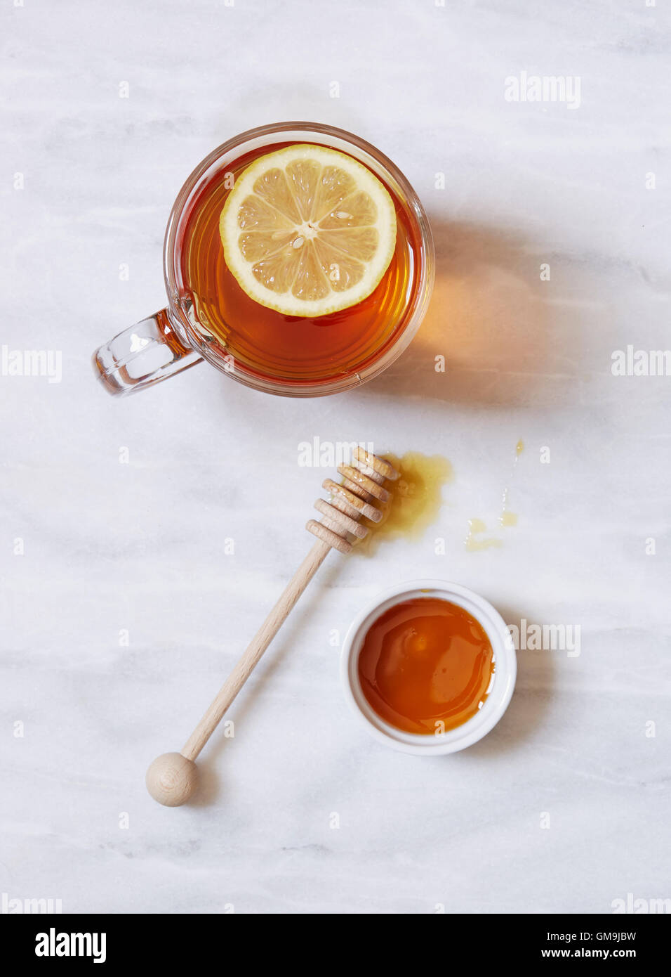 Draufsicht der Tasse Tee mit Zitrone und Schale mit Honig auf Marmortisch Stockfoto