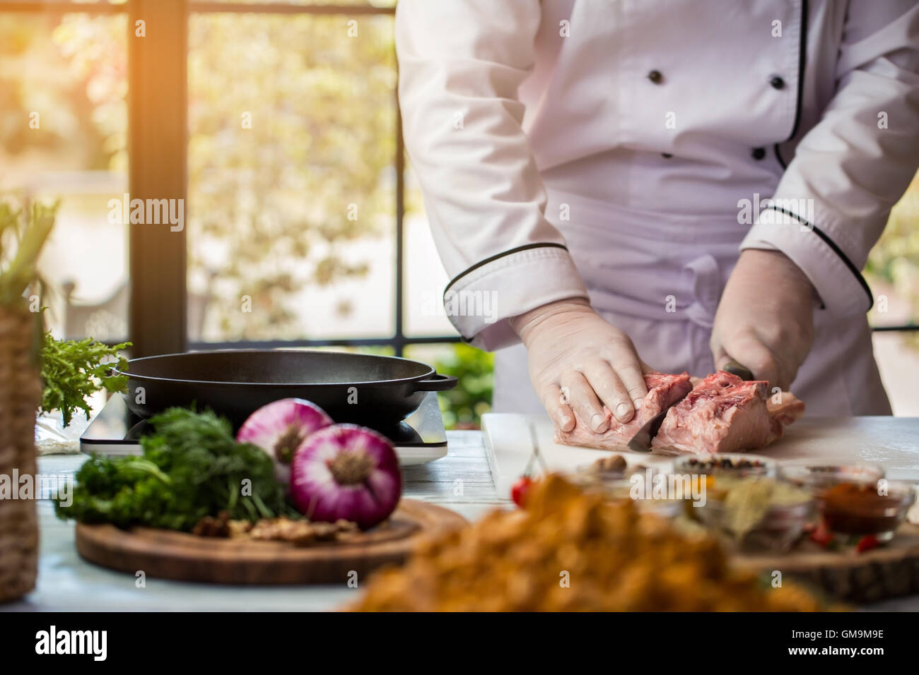 Mann mit Messer schneidet Fleisch. Stockfoto