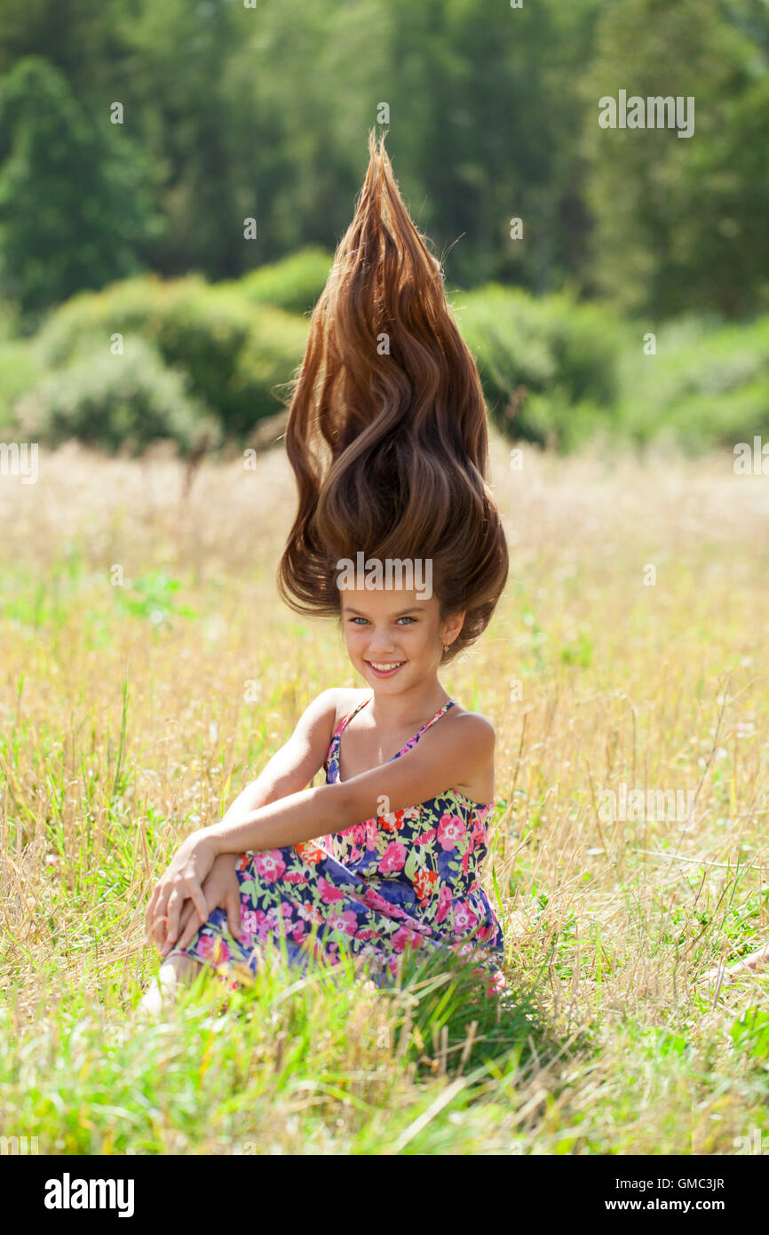 Brünette Haare, Schönheit. Porträt eines schönen Mädchens auf dem Hintergrund der Sommerwiese Stockfoto