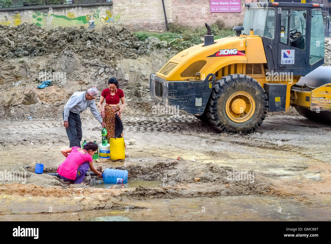 Eine lokale Familie sammelt Wasser aus einem gebrochenen Rohr in Kathmandu, Nepal. Stockfoto