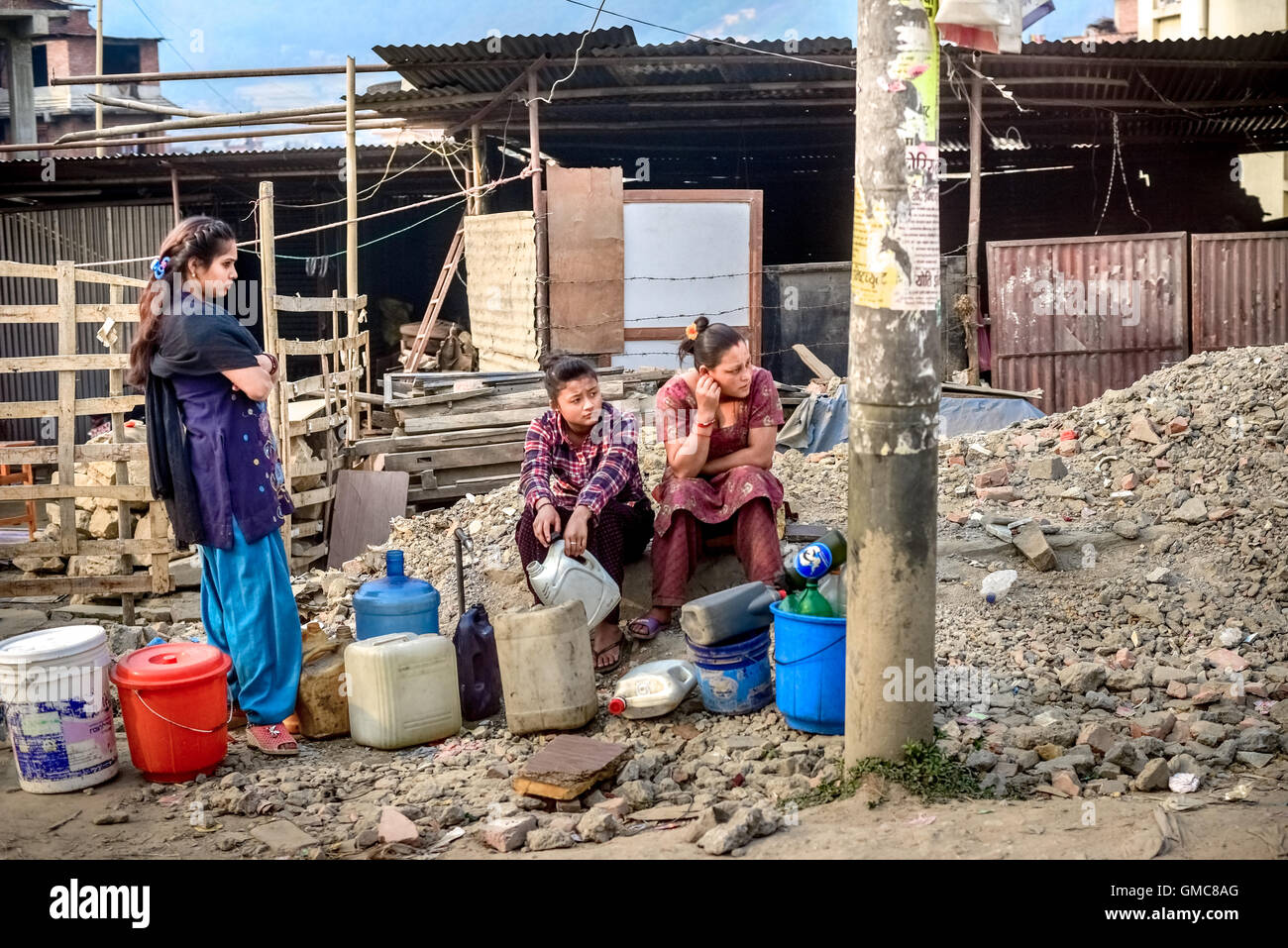 Während der Trockenzeit in Kathmandu, ein Jahr nach den Erdbeben in Nepal 2015, warten Frauen vor provisorischen Unterkünften auf einen Wasserwagen. Stockfoto