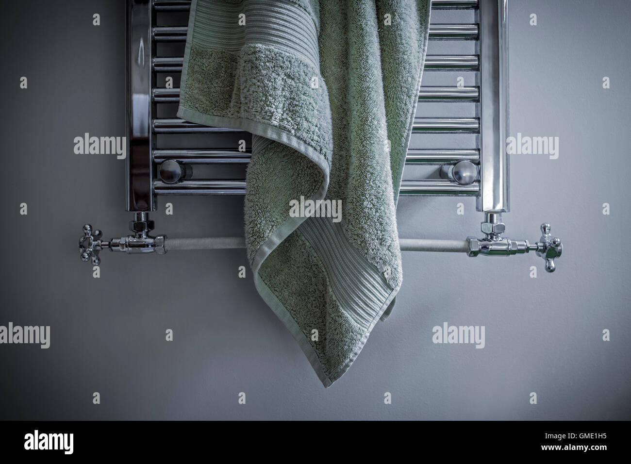 Badetuch unordentlich an einem beheizten Handtuchhalter hängen. Stockfoto