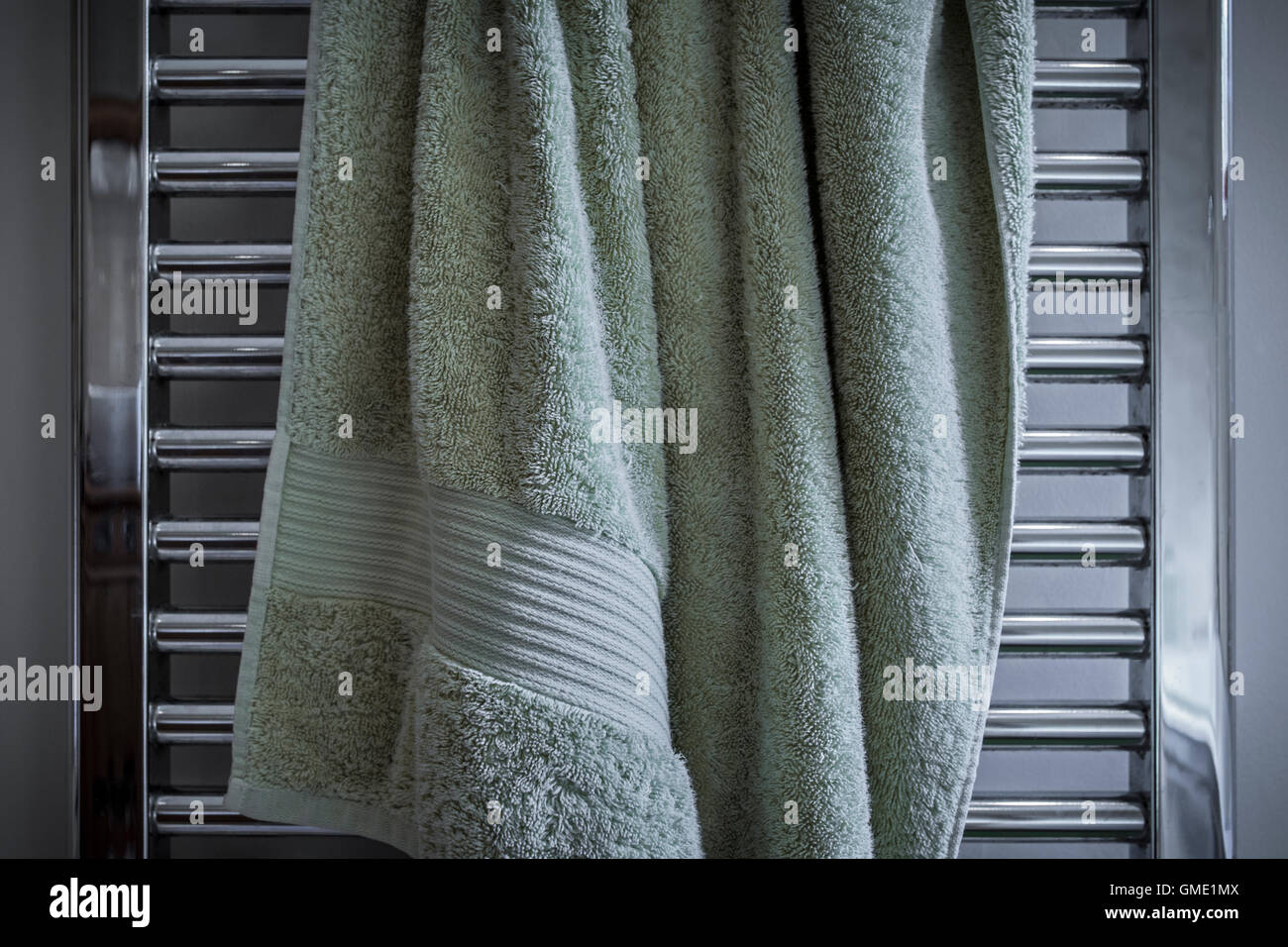 Badetuch unordentlich an einem beheizten Handtuchhalter hängen. Stockfoto
