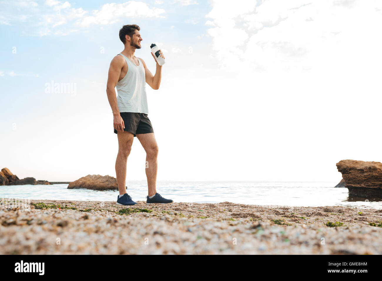 Sportlicher junger Mann Sportler ausruhen nach dem Joggen am Strand und im Wasser Stockfoto
