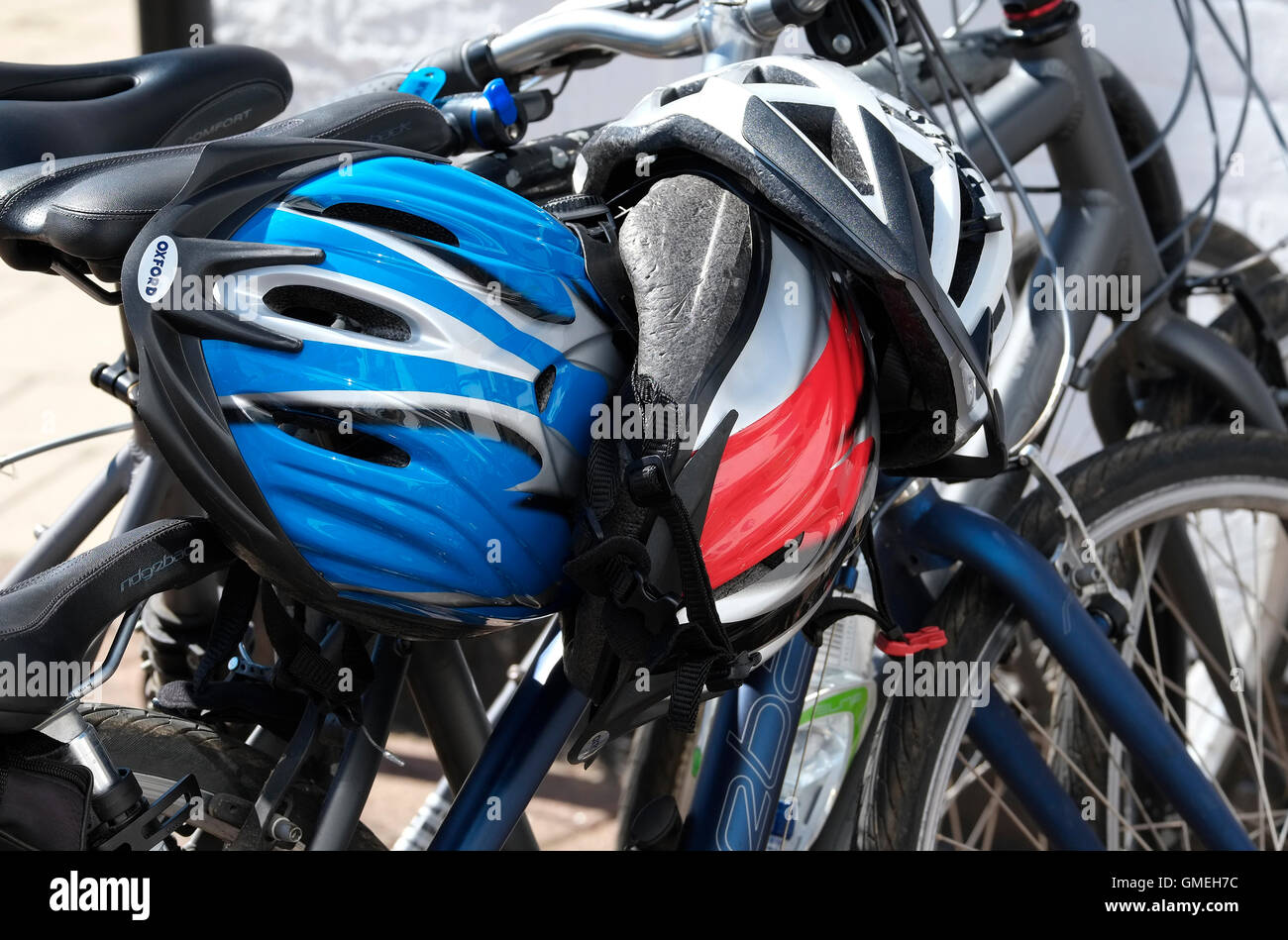 Zyklus-Helme an geparkten Fahrrädern befestigt Stockfoto