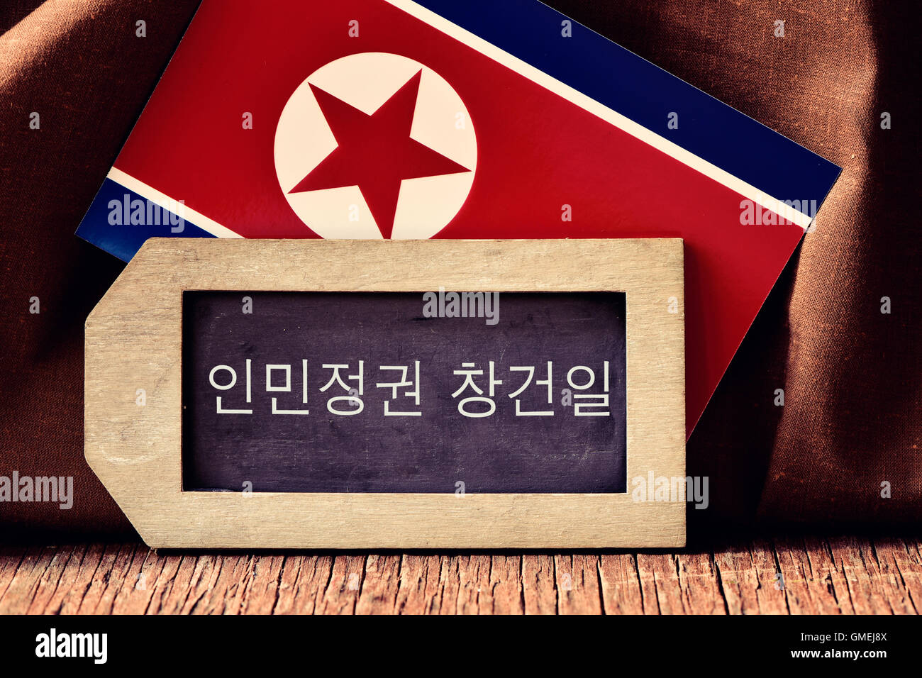 der Text der Gründungstag der Republik in ein Label-förmigen Tafel und eine Fahne von Nordkorea, auf eine r in Koreanisch geschrieben Stockfoto
