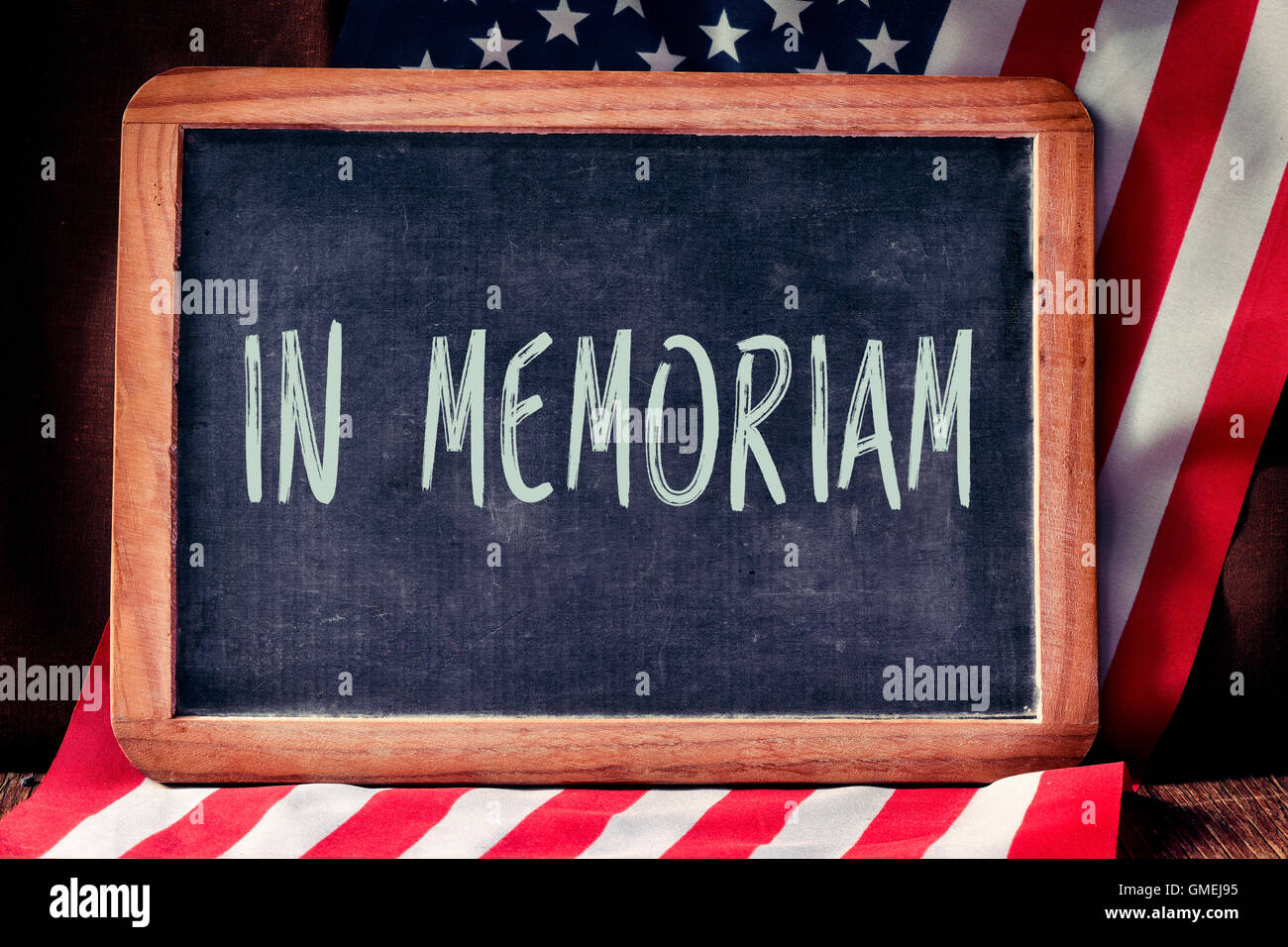 der Text in Memoriam in eine Tafel und eine Flagge der Vereinigten Staaten auf eine rustikale Holzoberfläche geschrieben Stockfoto