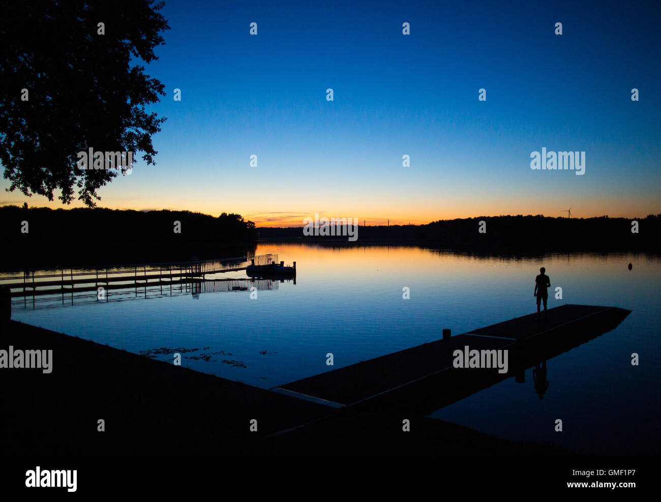 Haltern am See, Deutschland. 24. August 2016. Die Silhouette eines Mannes ist gegen das blaue Wasser beim Sonnenuntergang am Ufer des Stausees in Haltern am See, Deutschland, 24. August 2016 skizziert. Foto: Marcel Kusch/Dpa/Alamy Live News Stockfoto