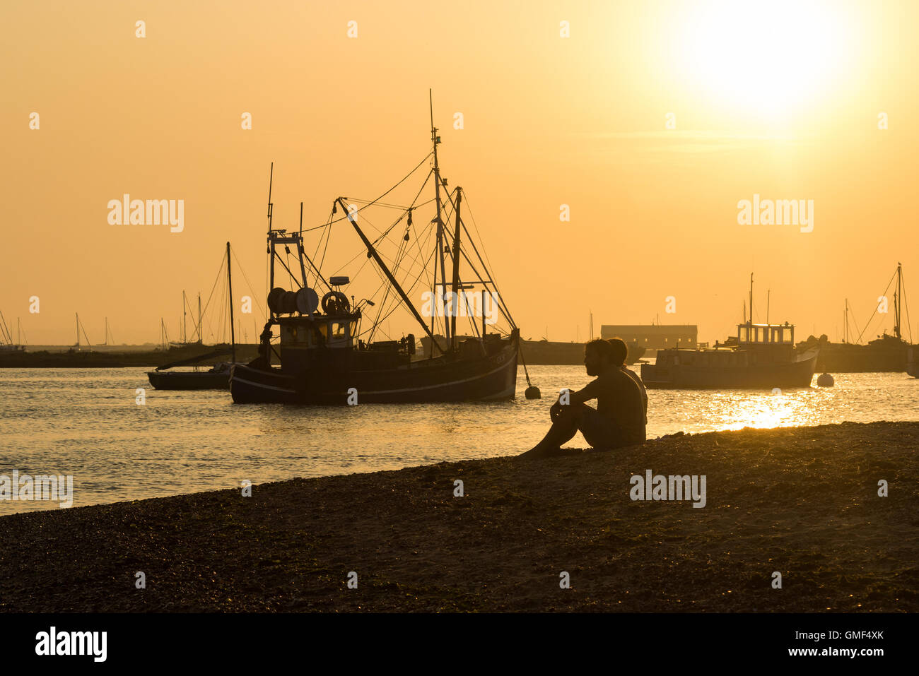 Mersey Insel, Essex, 25. August 2016.  Ein paar am Strand entspannen als Balken ruht Trawler vor Anker, als die Sonne untergeht. Bildnachweis: Paul Davey/Alamy Live-Nachrichten Stockfoto