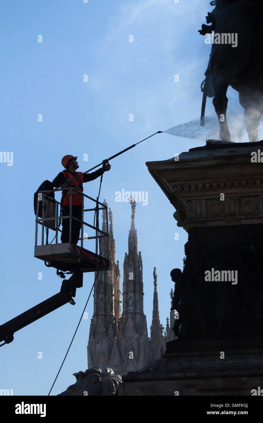 Arbeiter Reinigung Vogelkot mit hohem Druckwasser aus dem Denkmal für König Victor Emmanuel II von Italien, entworfen von dem italienischen Bildhauer Ercole Rosa auf der Piazza del Duomo in Mailand, Lombardei, Italien. Marmor-Türme von der Mailänder Dom (Duomo di Milano) sind im Hintergrund zu sehen. Stockfoto