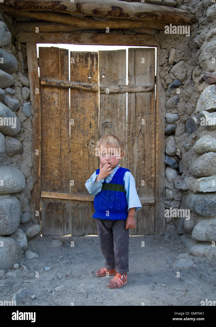 Afghanischer Junge mit blonden Haaren vor einer hölzernen Tür, Badakhshan Provinz Khandood, Afghanistan Stockfoto