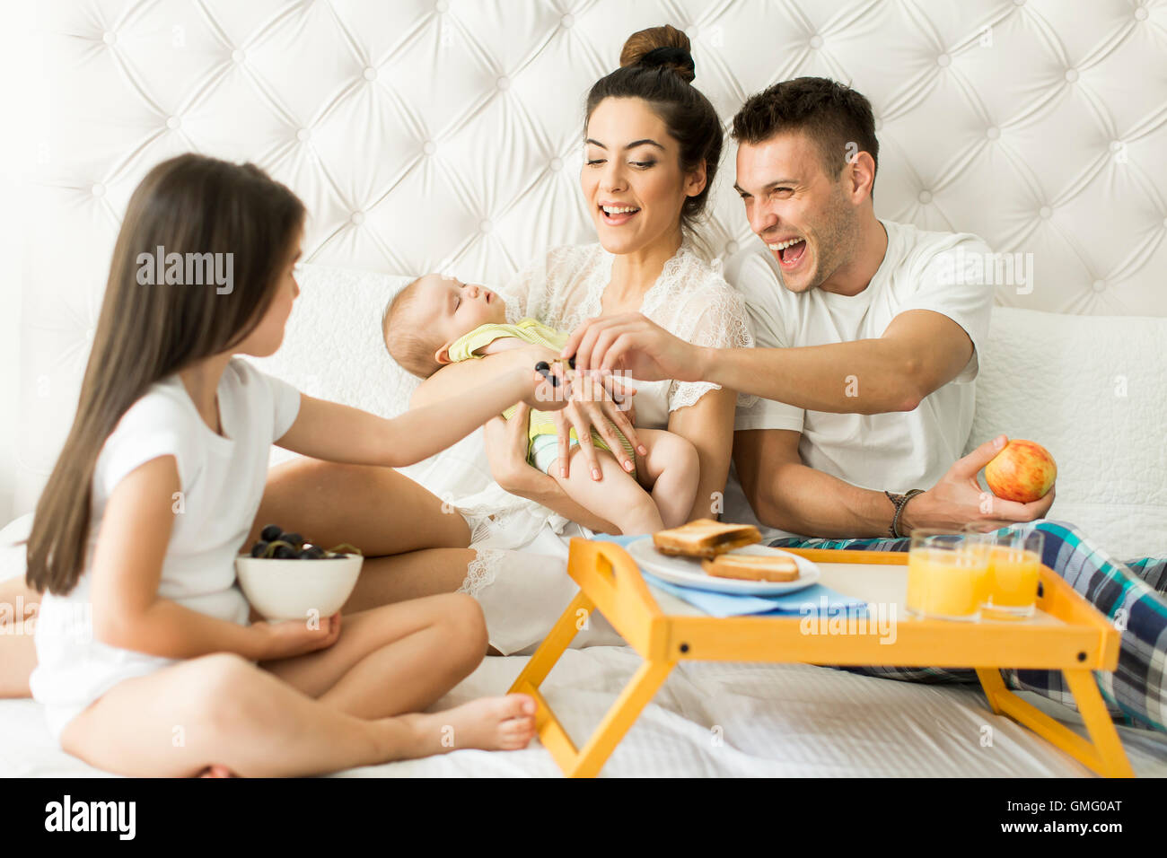 Mutter, Vater, Kind und kleine Mädchen auf dem Bett im Zimmer Stockfoto