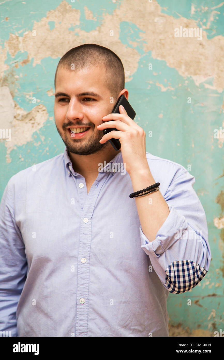 Junger Mann mit einem Telefon von alten Grunge-Mauer Stockfoto