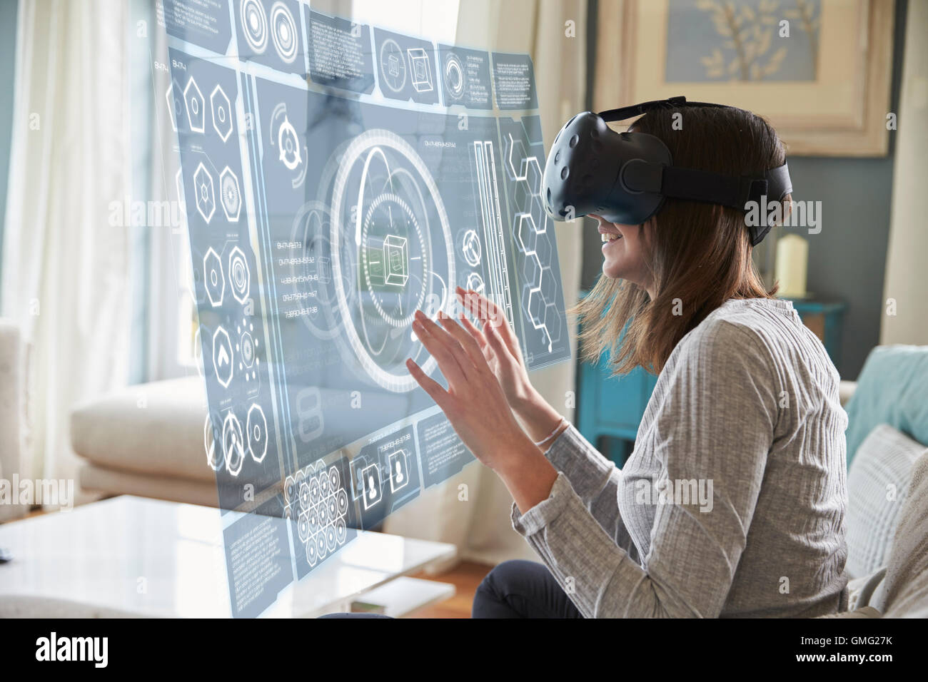 Frau sitzt auf dem Sofa zu Hause tragen Virtual-Reality-Kopfhörer Stockfoto