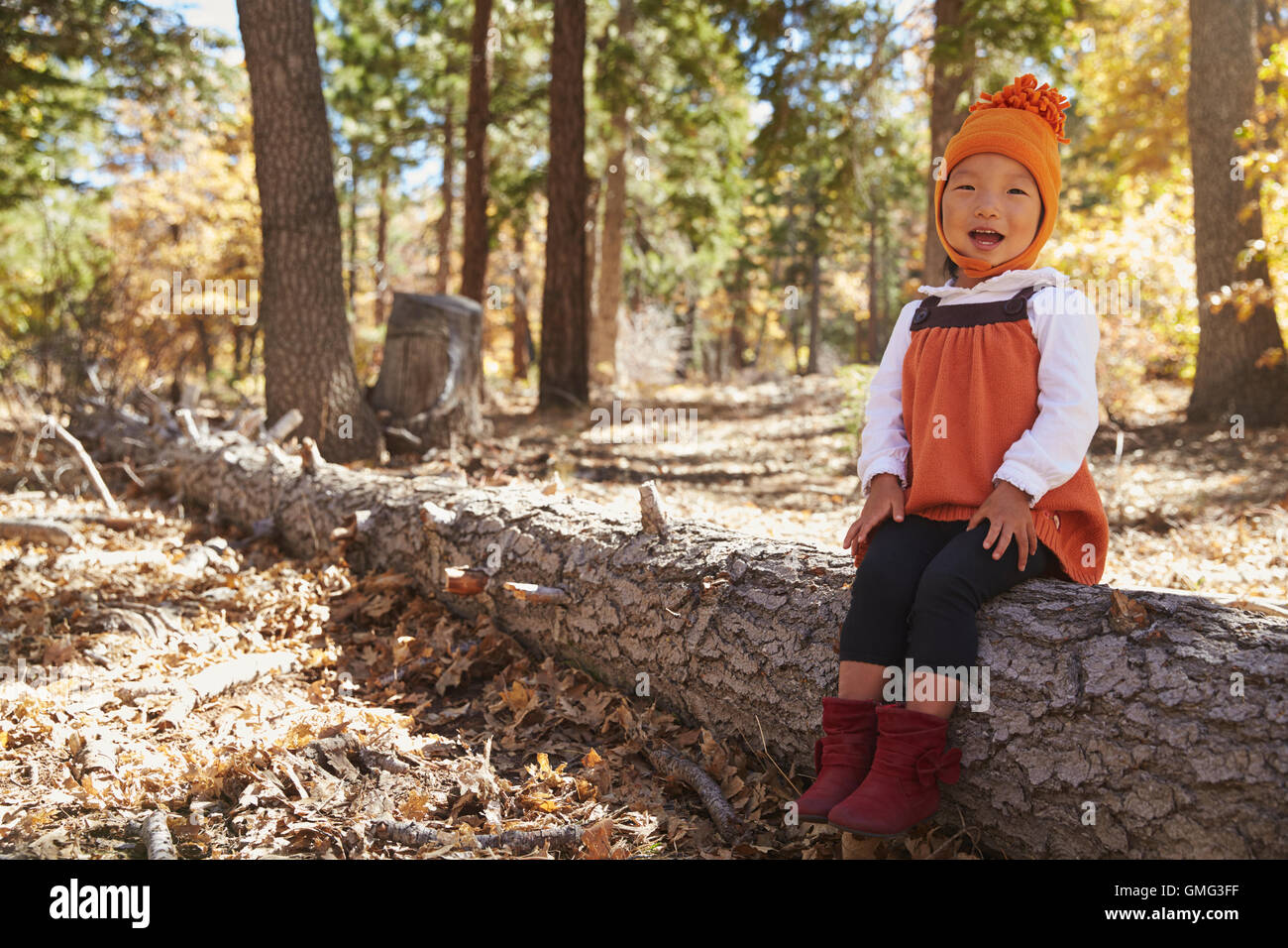 Asiatische Kleinkind Mädchen sitzen in einem Wald auf Kamera Stockfoto