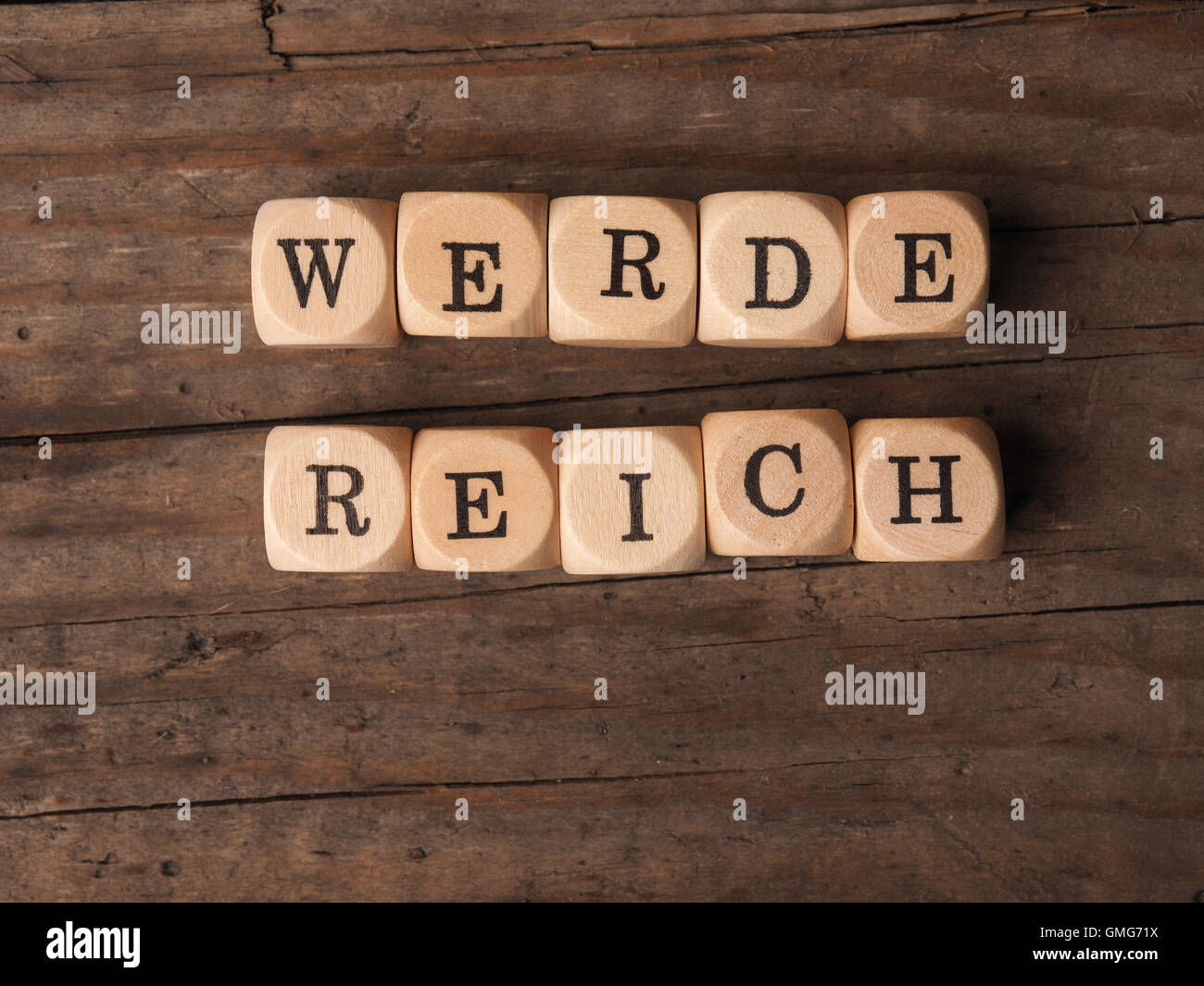 Hölzernen Würfel mit den deutschen Worten werde reich auf einem Holztisch Stockfoto