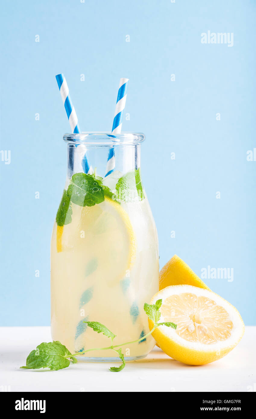 Flasche hausgemachten Limonade mit Minze, Eis, Zitronen, Papier Strohhalme und Pastell blau Hintergrund Stockfoto