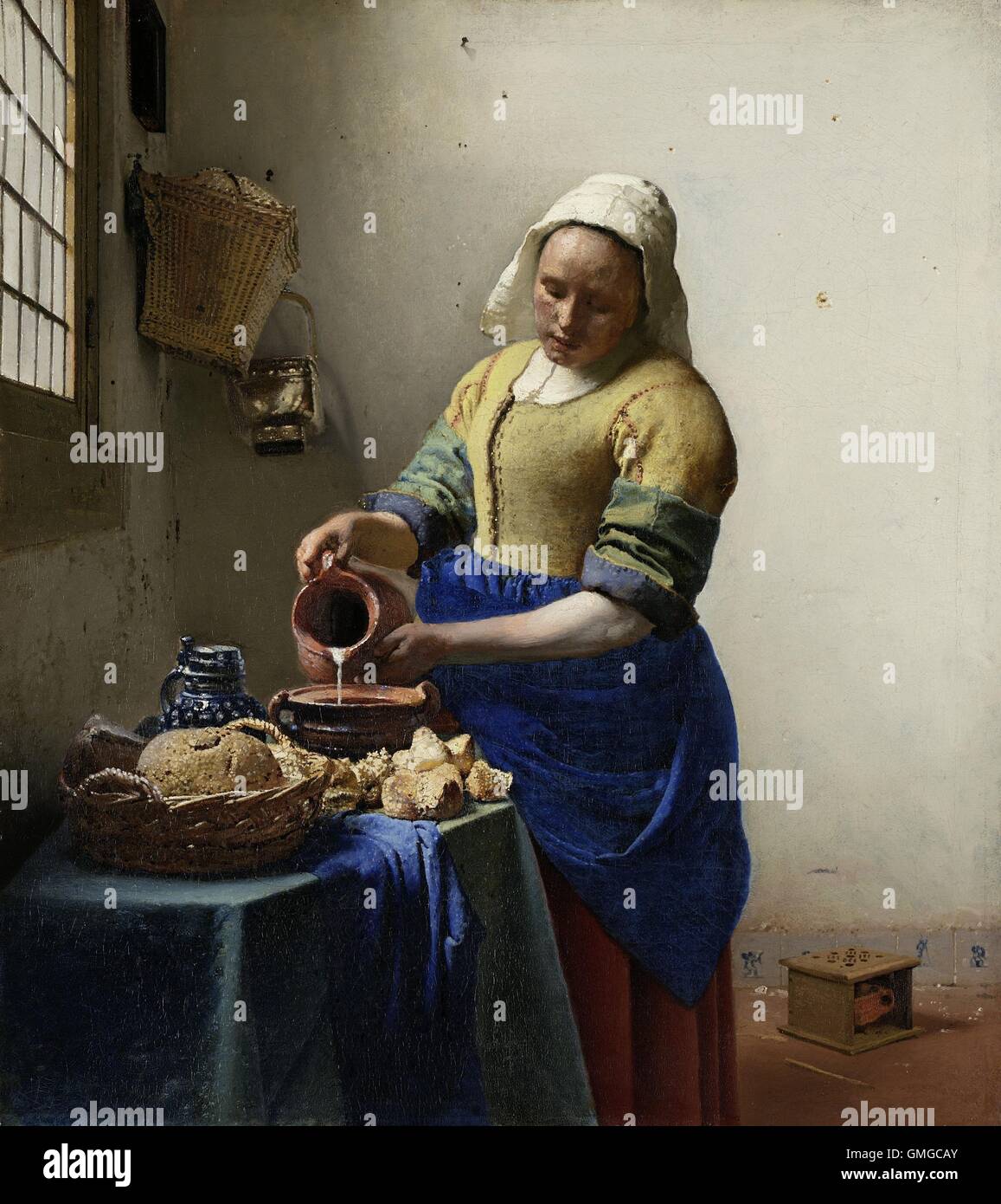 Das Milchmädchen von Johannes Vermeer, 1660, niederländische Malerei, Öl auf Leinwand. Von Licht aus einem Fenster beleuchtet, ergießt sich eine junge Frau Stockfoto