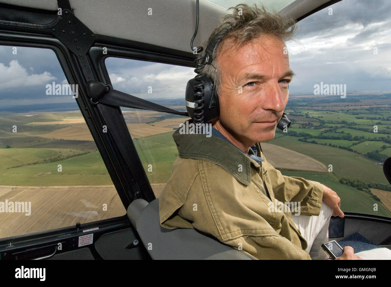 Crop Circle Ermittler Clive Aslet (Croppy/Kornkreisfreaks) auf der Suche nach Kornkreise in Wiltshire, Großbritannien, mit einem Hubschrauber und mit Blick auf Mais flach Stockfoto