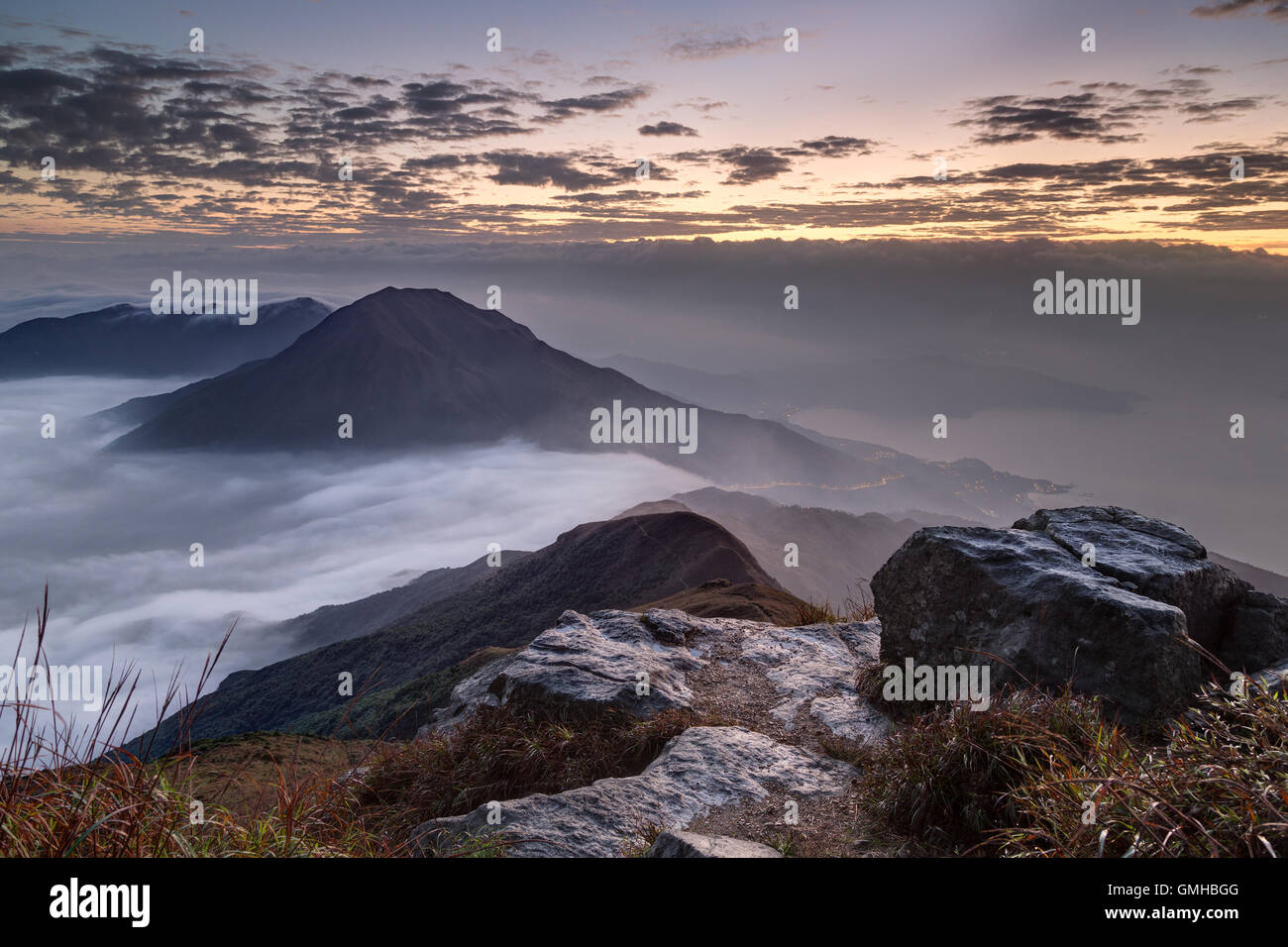 Wolken überrollen Berg auf Lantau Island, gesehen vom Lantau Peak (der 2. höchste Berg in Hongkong, China) in der Morgendämmerung. Stockfoto