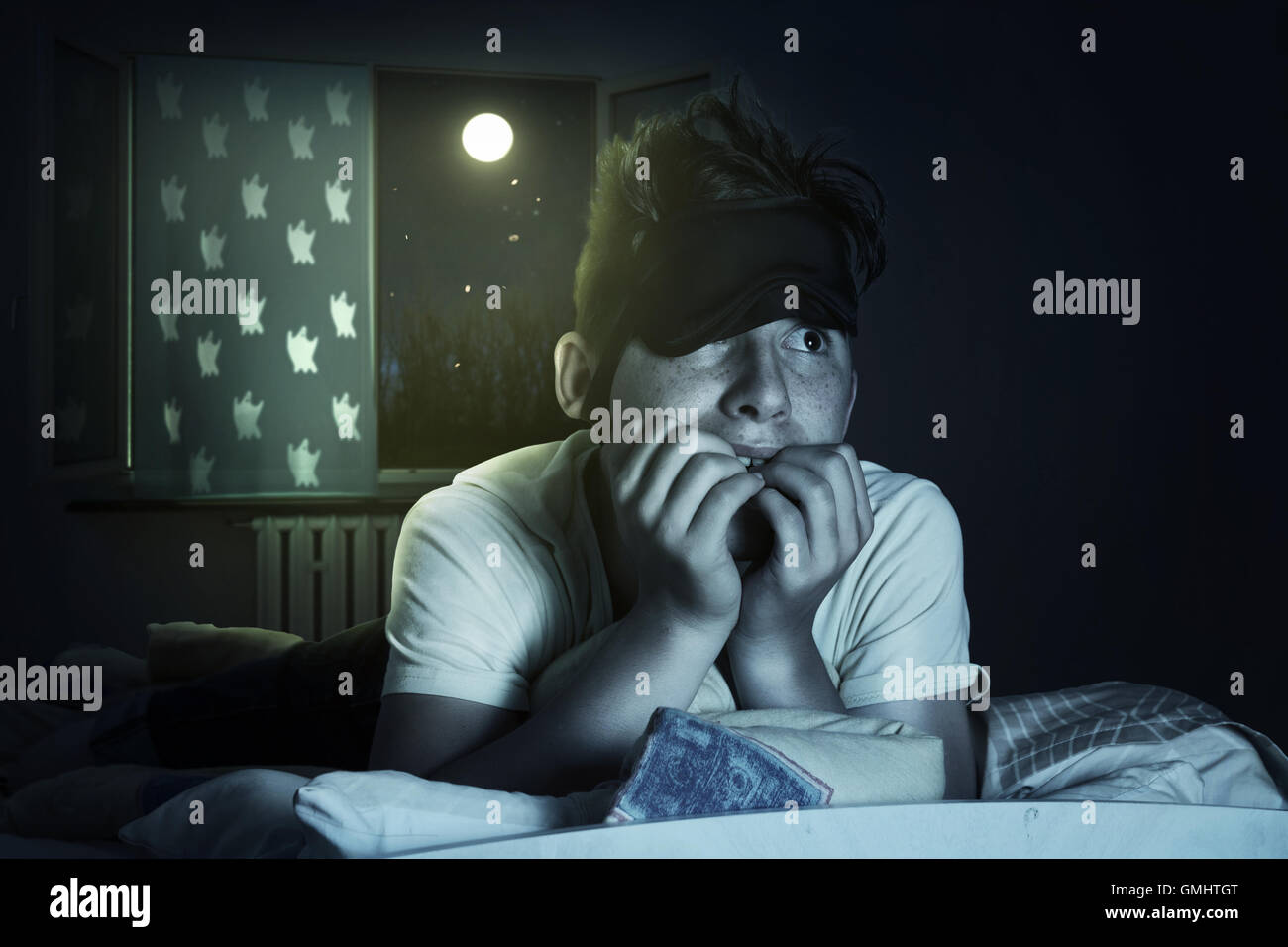 Angst und schlaflosen junge kauen Fingernägel im Schlafzimmer vor glänzenden Mond Stockfoto