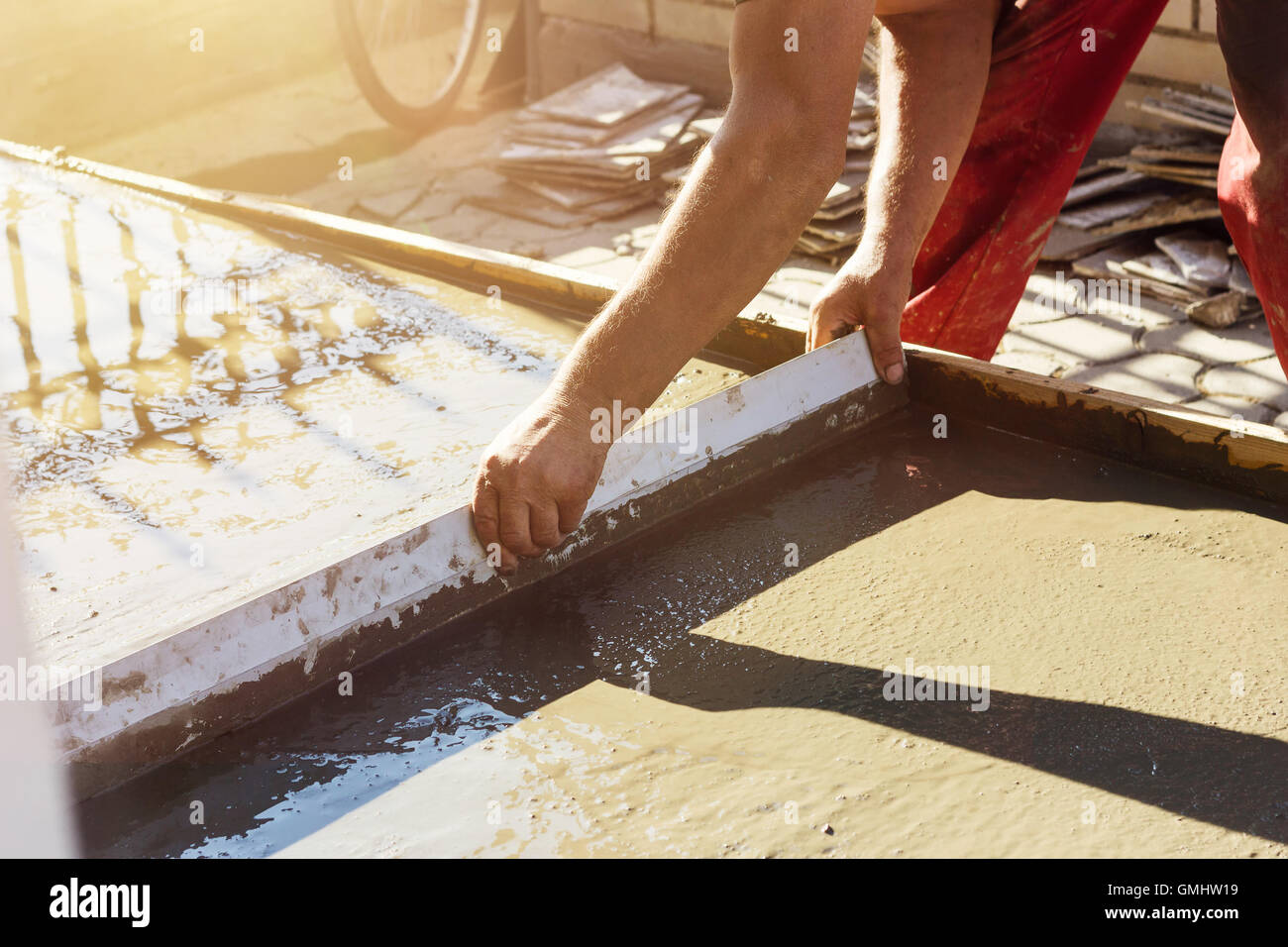 Nivellierung nassen Betonoberfläche mit einem Metall Estrich Brett in Abendsonne Stockfoto