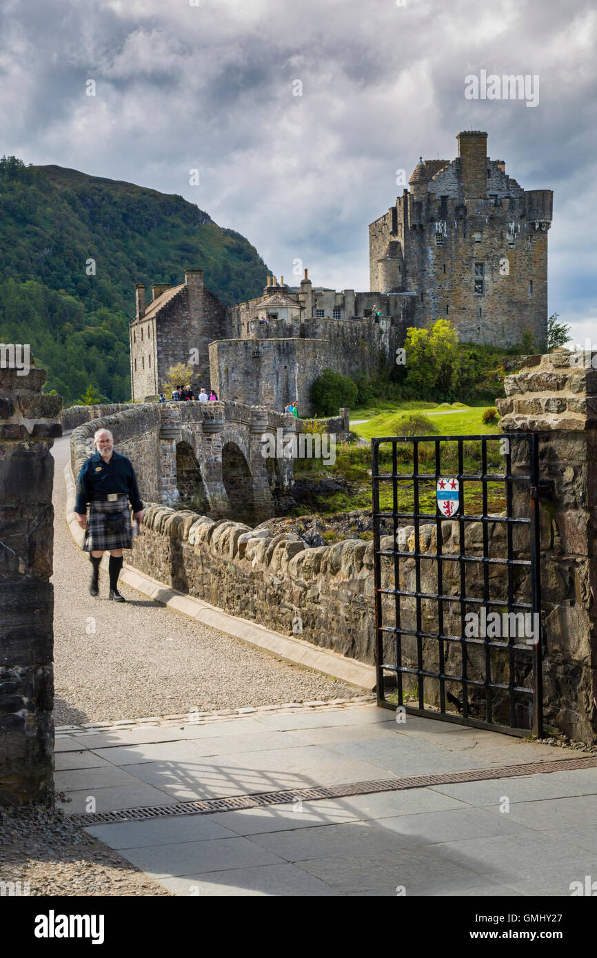 Mann in einem Kilt geht über die Brücke von Eilean Donan Castle, Highlands, Schottland, UK Stockfoto