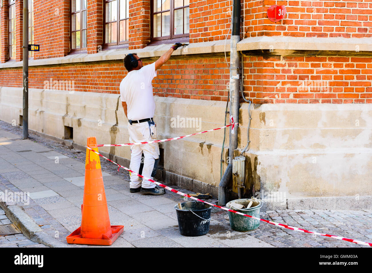 Lund, Schweden - 24. August 2016: Mason arbeitet mit Reparaturen an einem Gebäude auf Straßenniveau. Alltägliche Stadtleben. Stockfoto