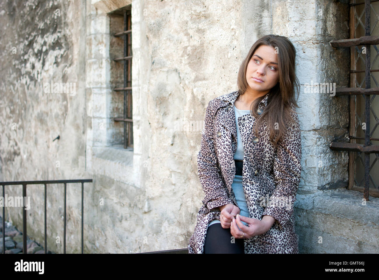 Mädchen in Leopard Fell aufgewirbelt auf der Straße, in der Nähe der Fenster des alten bulidingl Stockfoto