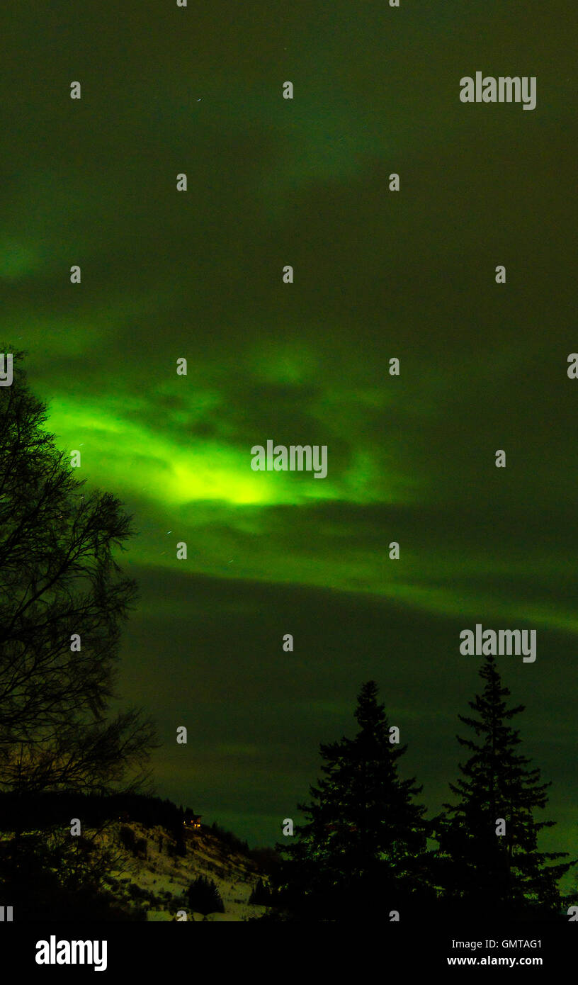 Ein Loch in den Wolken kann grünes Licht von einer Aurora durchscheinen. Stockfoto